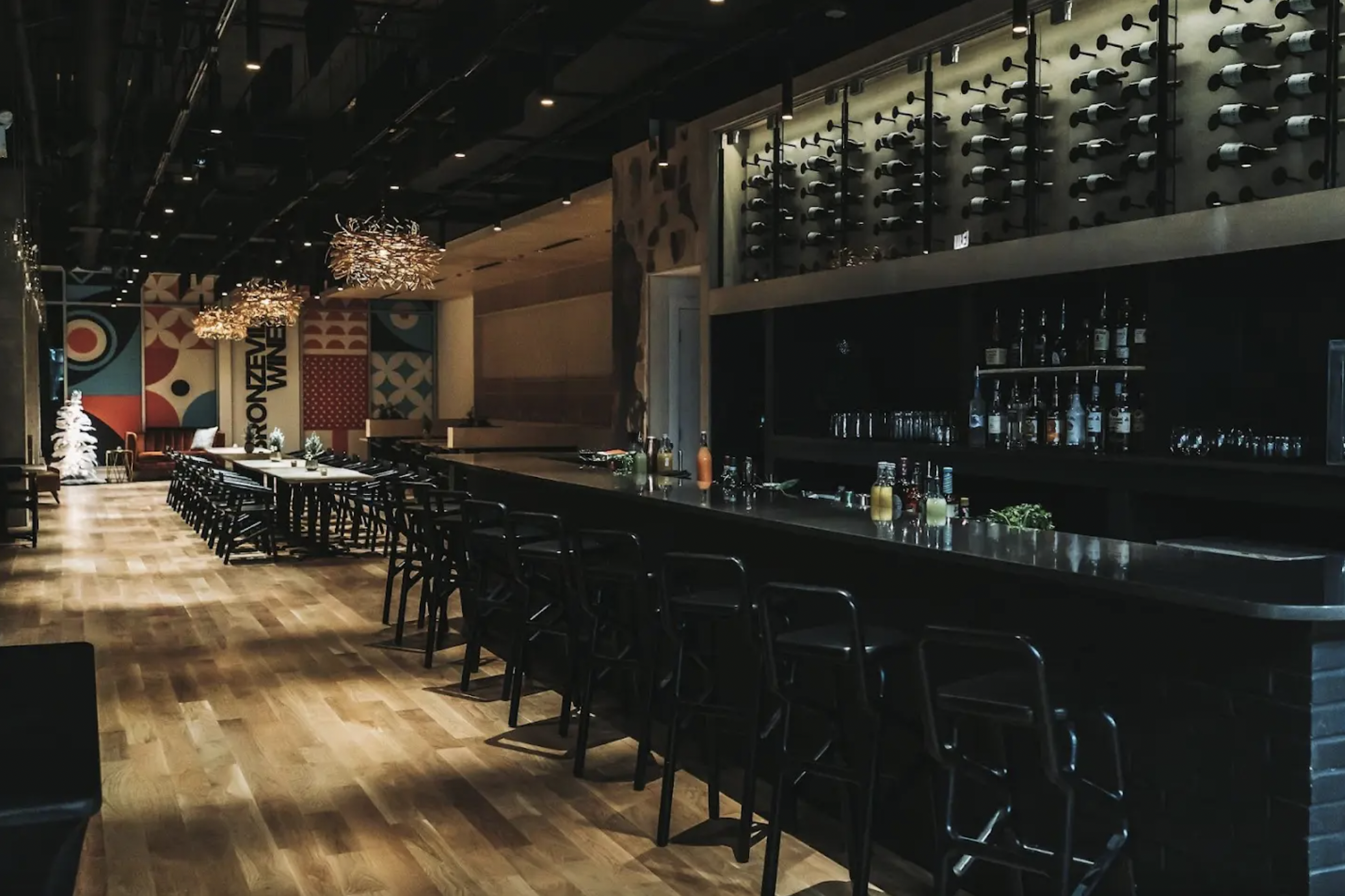 A long restaurant space with a dark bar and natural wood floors.
