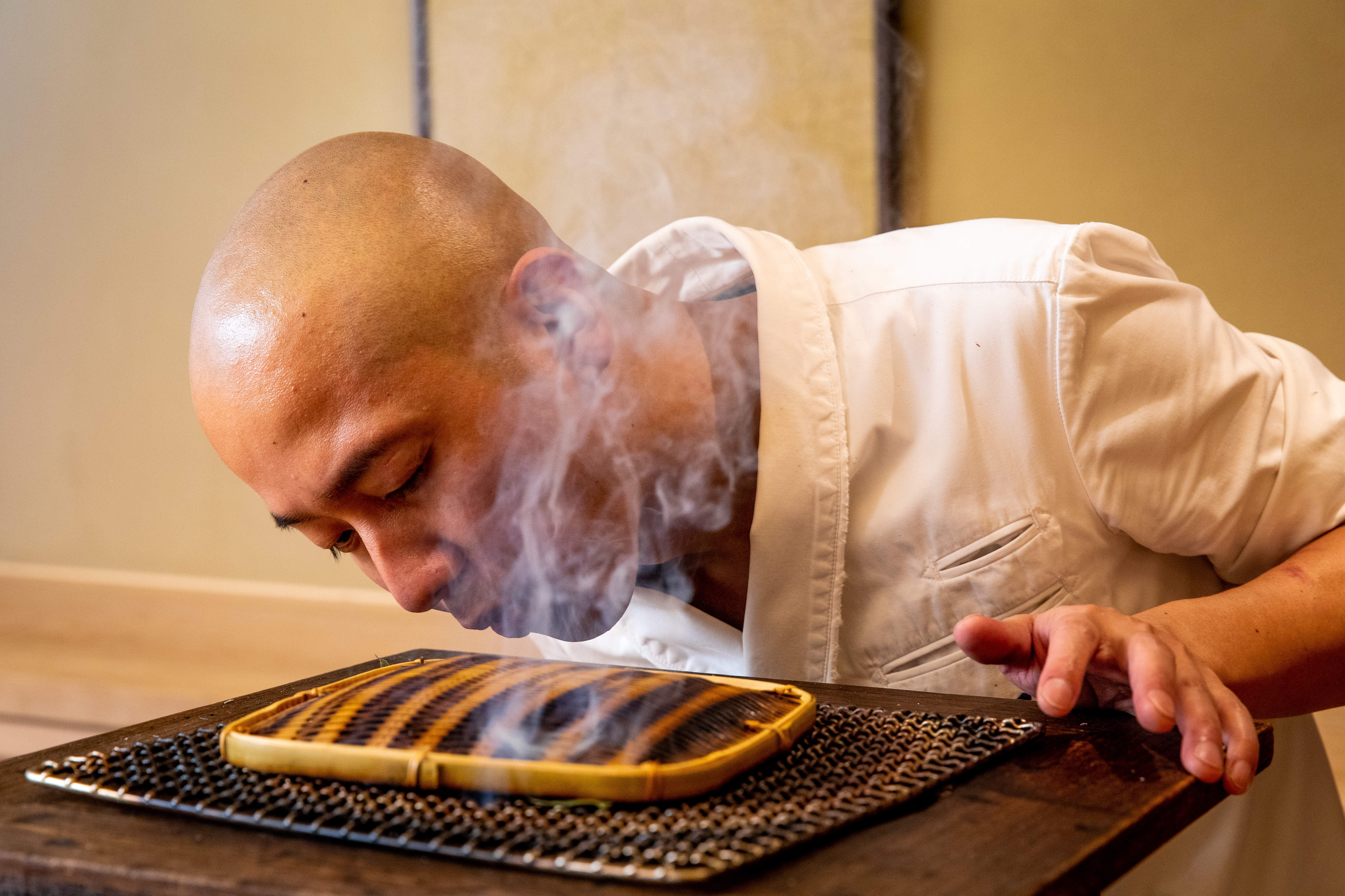 Noz chef Nozomu Abe blows over a portable grill he’s using to lightly smoke sea eel