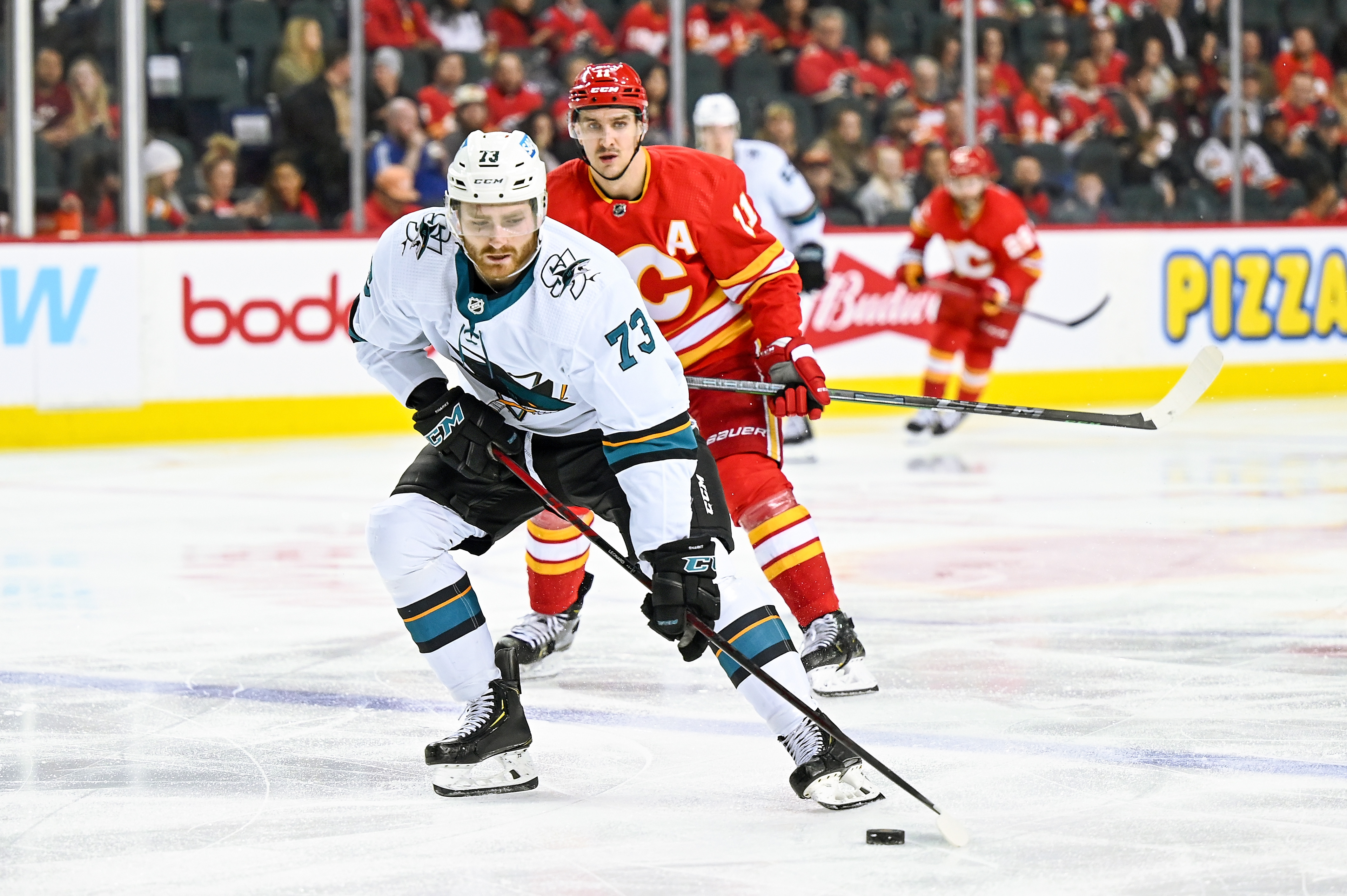 San Jose Sharks Winger Noah Gregor (73) skates with the puck while Calgary Flames Center Mikael Backlund (11) backchecks during the third period of an NHL game where the Calgary Flames hosted the San Jose Sharks on March 22, 2022, at the Scotiabank Saddledome in Calgary, AB.