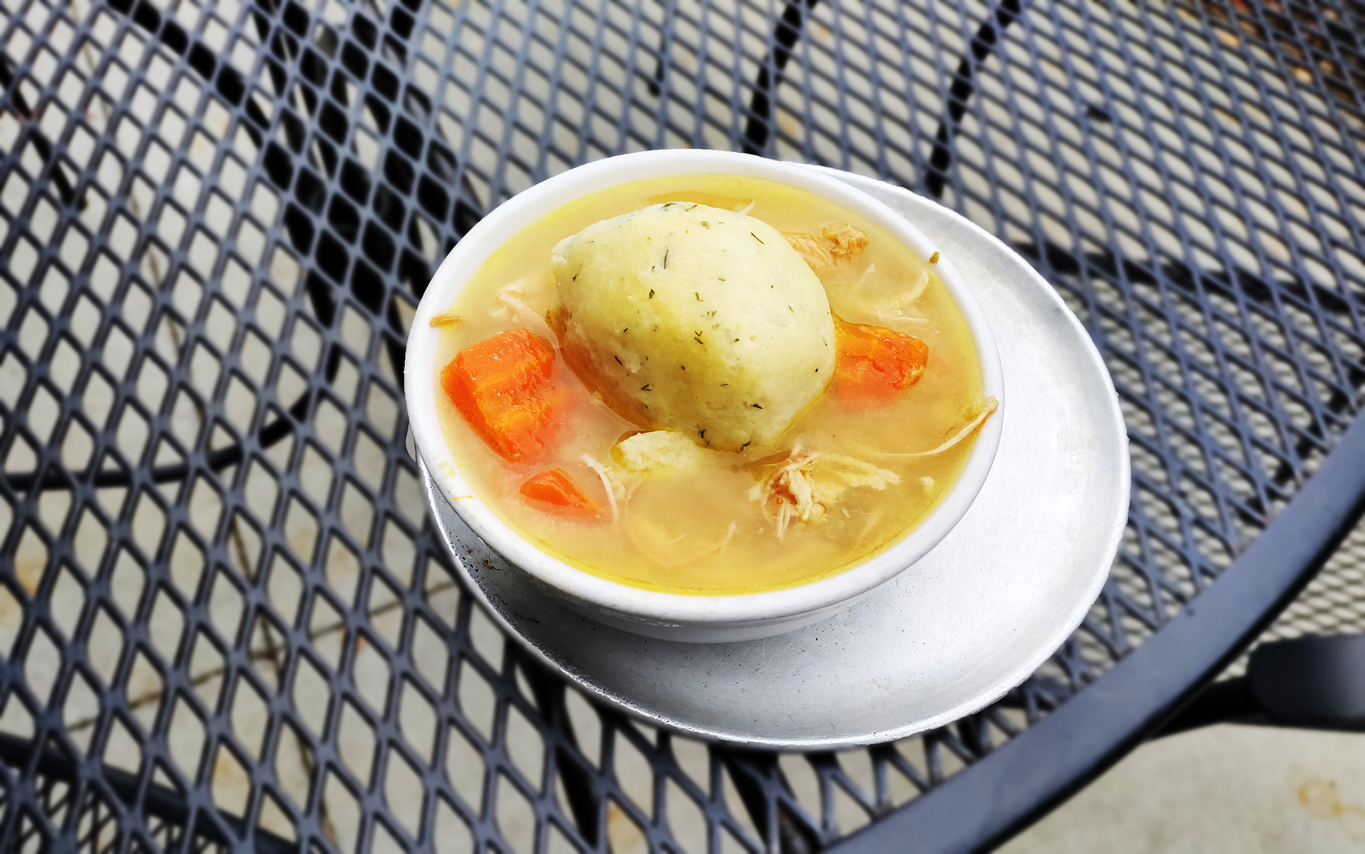Matzo ball soup on a patio table. 
