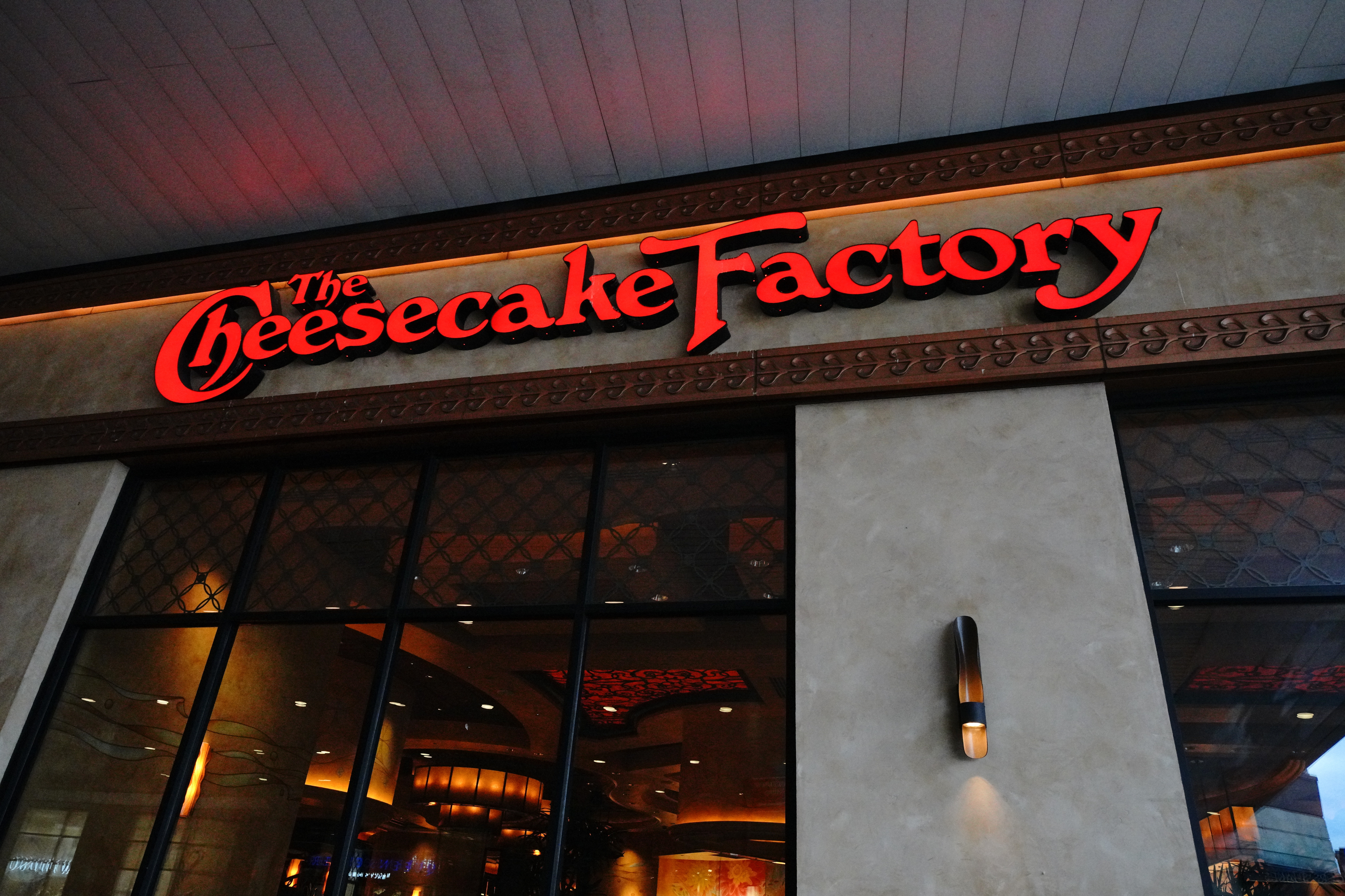 A neon red sign with the Cheesecake Factory logo.