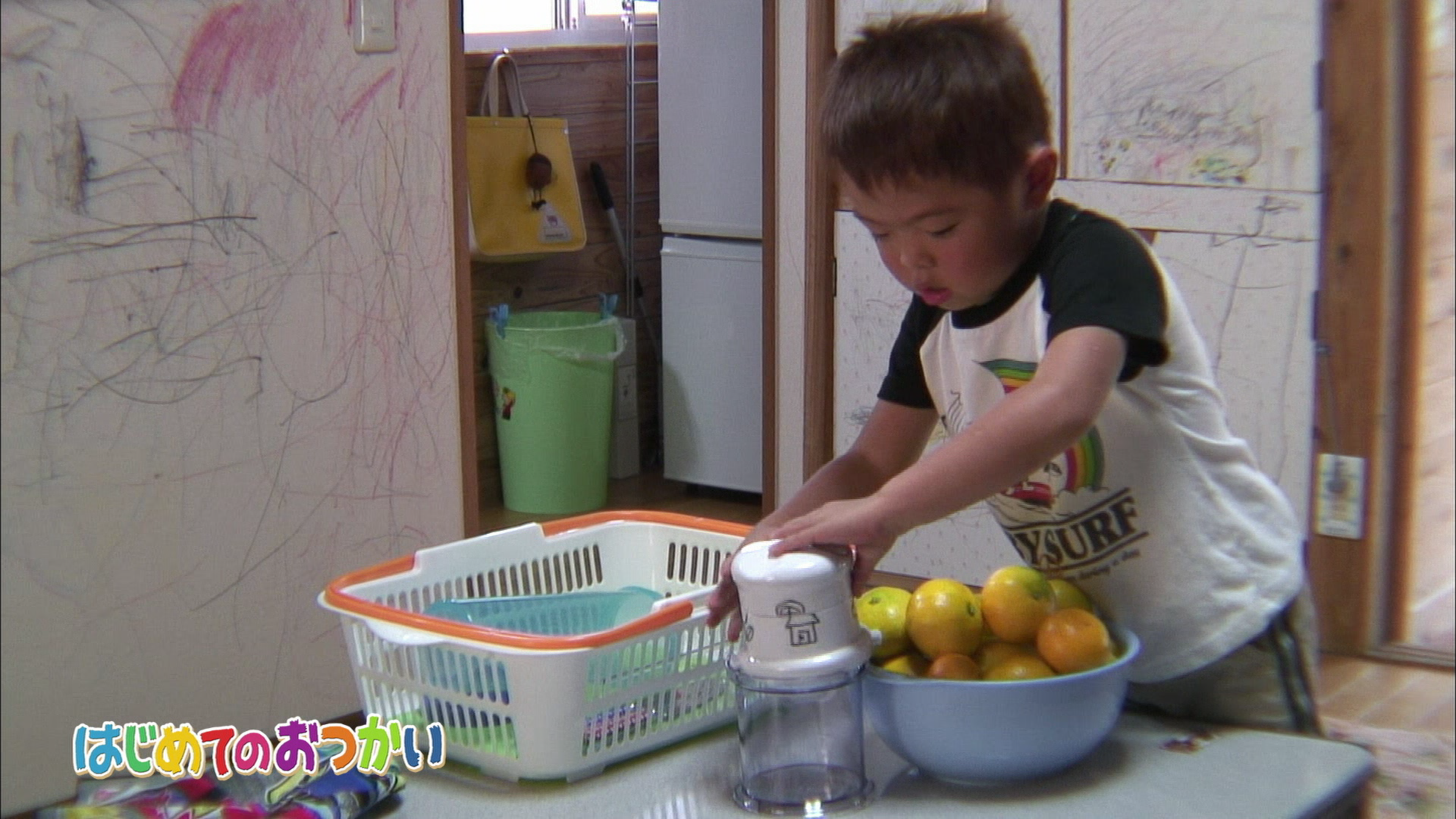 Small boy juices oranges with a juicer.