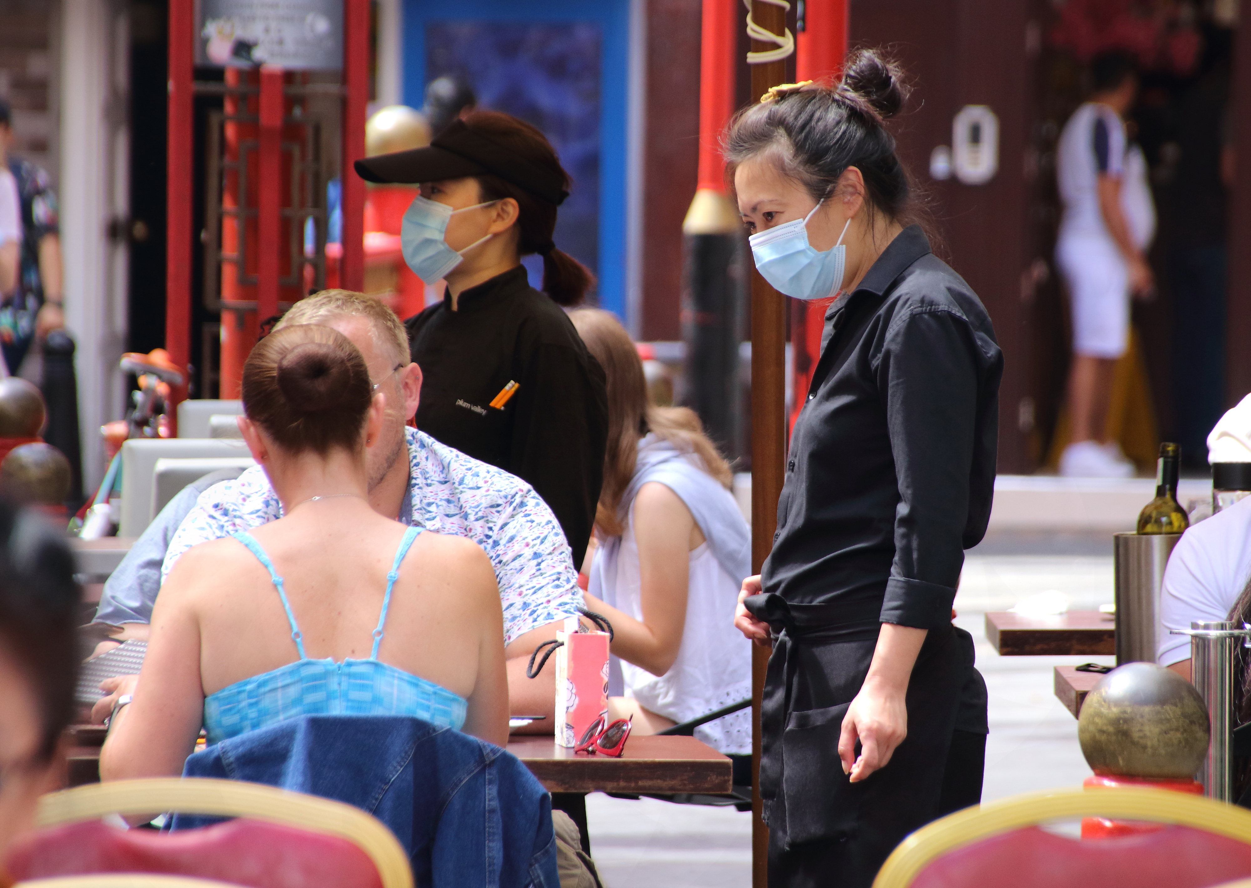 A waitress wears a facemask while she takes orders at a...