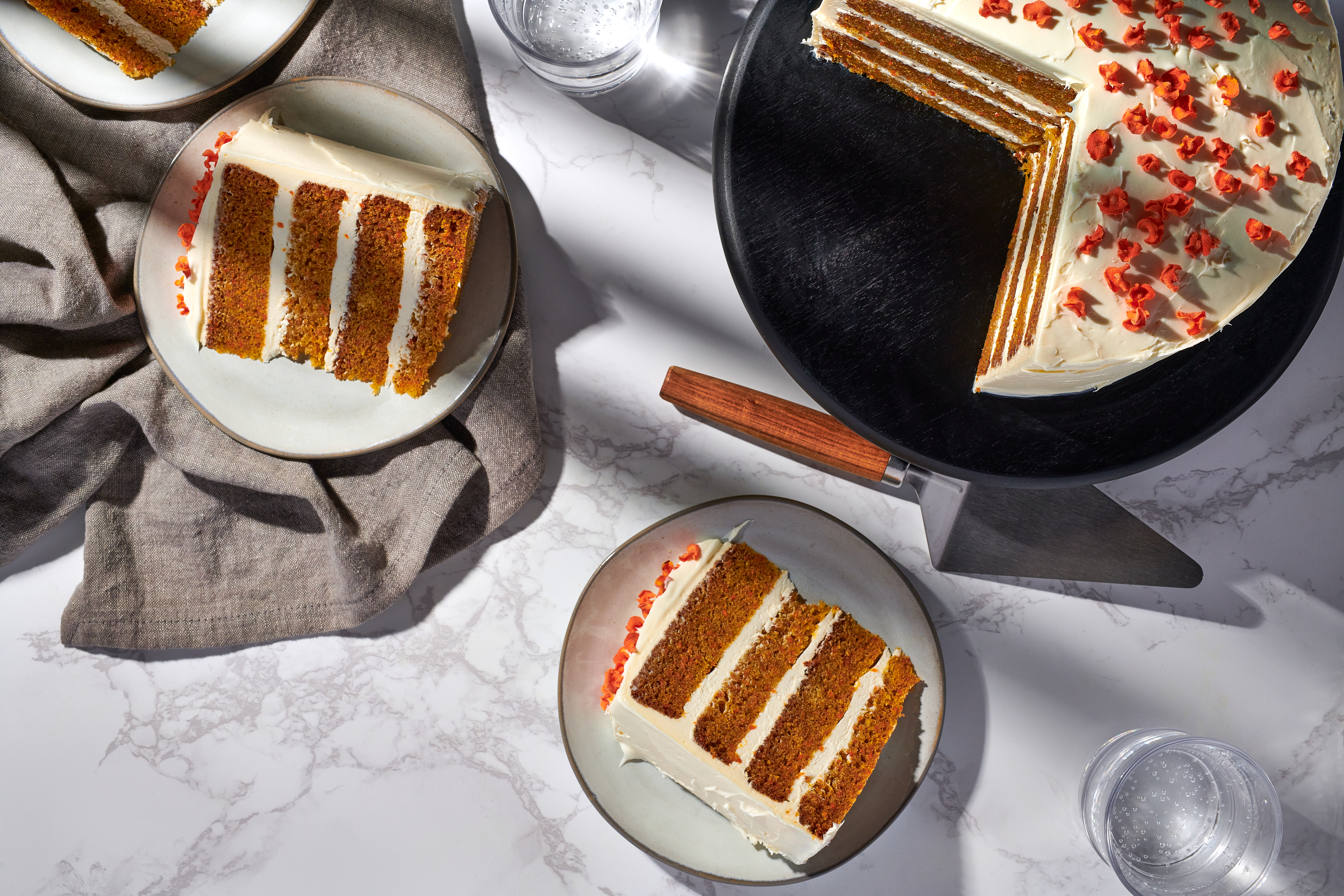 Two big slices of carrot cake are plated next to the rest of the cake. 