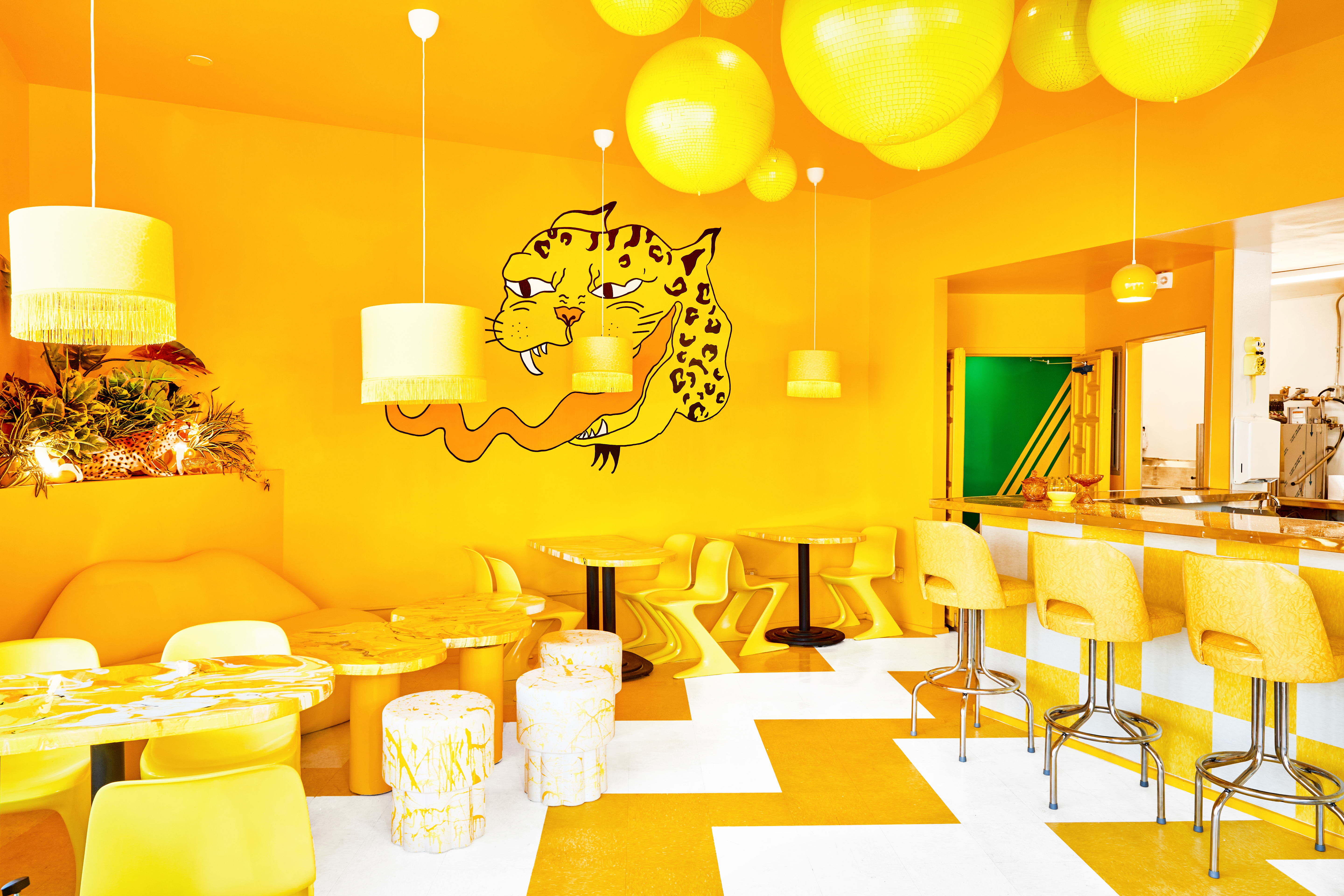 The monochromatic yellow dining room at Shuggie’s with a cheetah mural on the back wall.