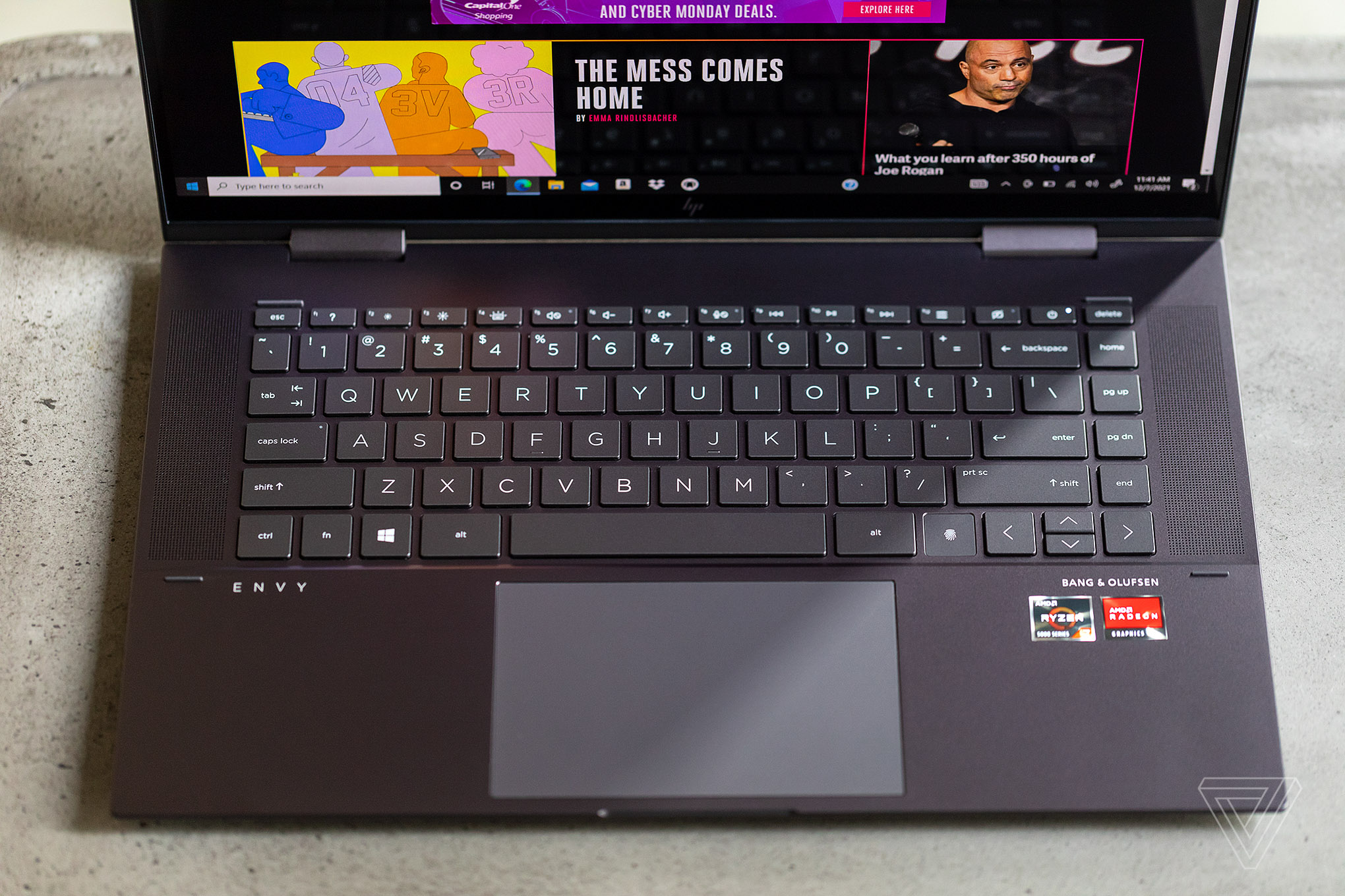 An HP Envy laptop keyboard seen from above with the bottom half of the screen visible. The screen displays The Verge homepage.