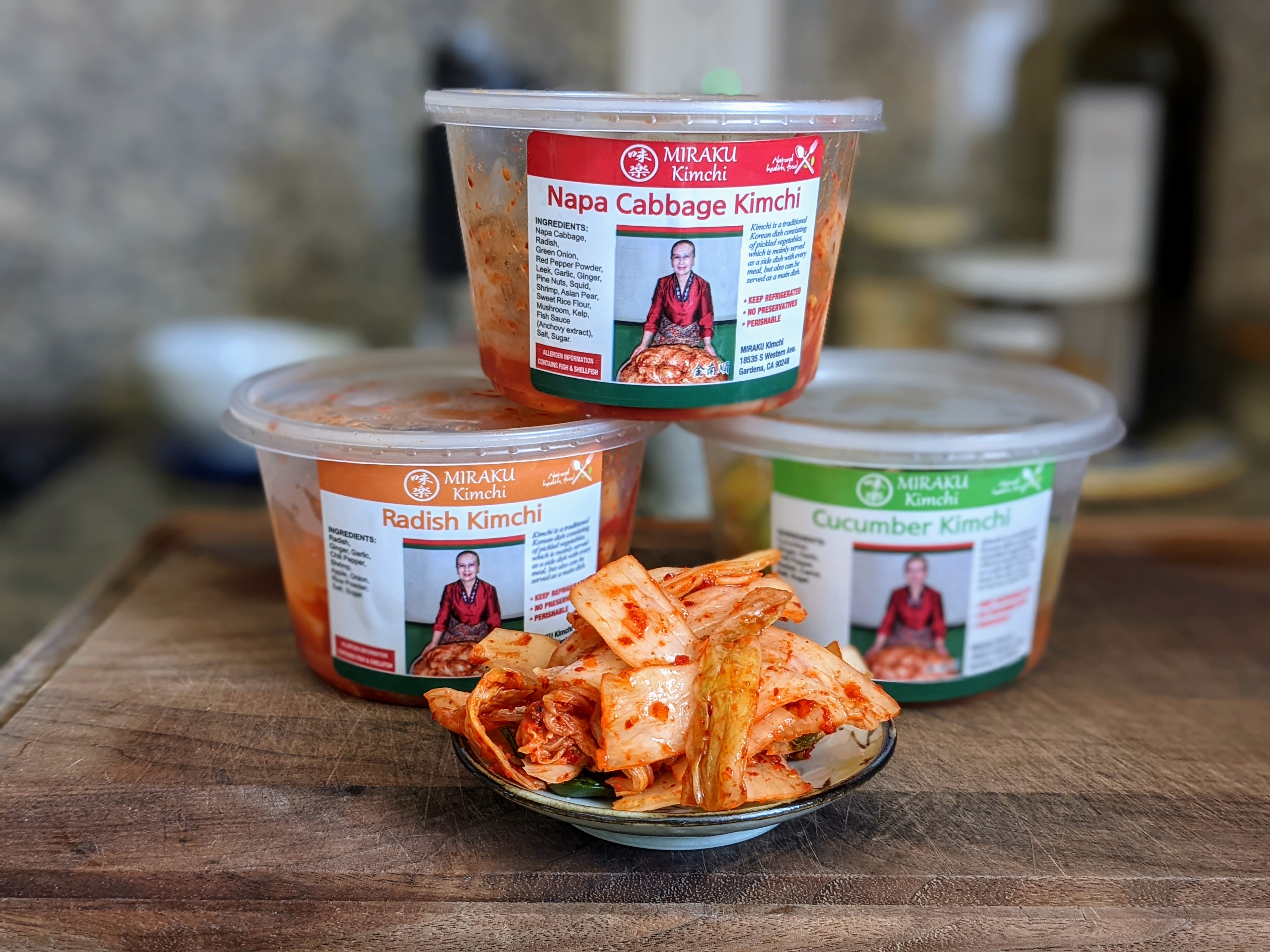 Bins of kimchi with some on a small plate.