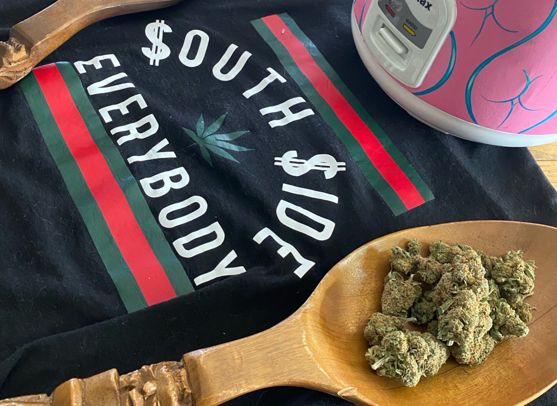 A wooden spoon with cannabis and a t-shirt reading “south side vs. everybody” using a weed plant instead of “Vs.”