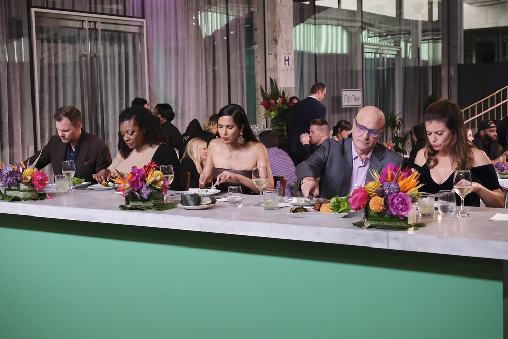 “Top Chef” judges Hunter Lewis, Tiffany Derry, Padma Lakshmi, Tom Colicchio, and Gail Simmons sit at a table, trying various dishes from Team No Nem.