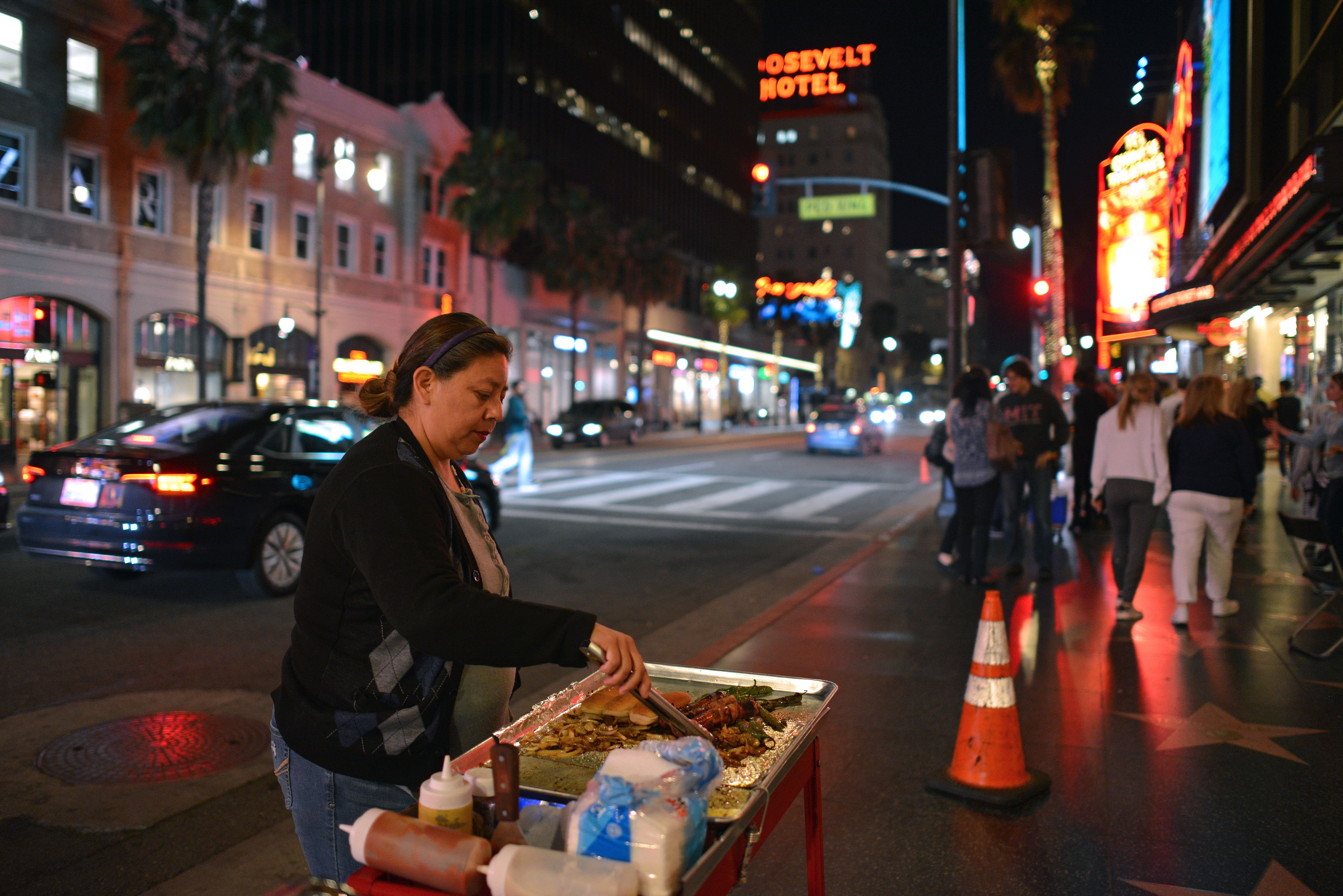 Maria Navas prepares hot dogs in front of the Dolby Theatre on the Hollywood Walk of Fame, in Los Angeles, on March 18, 2019.