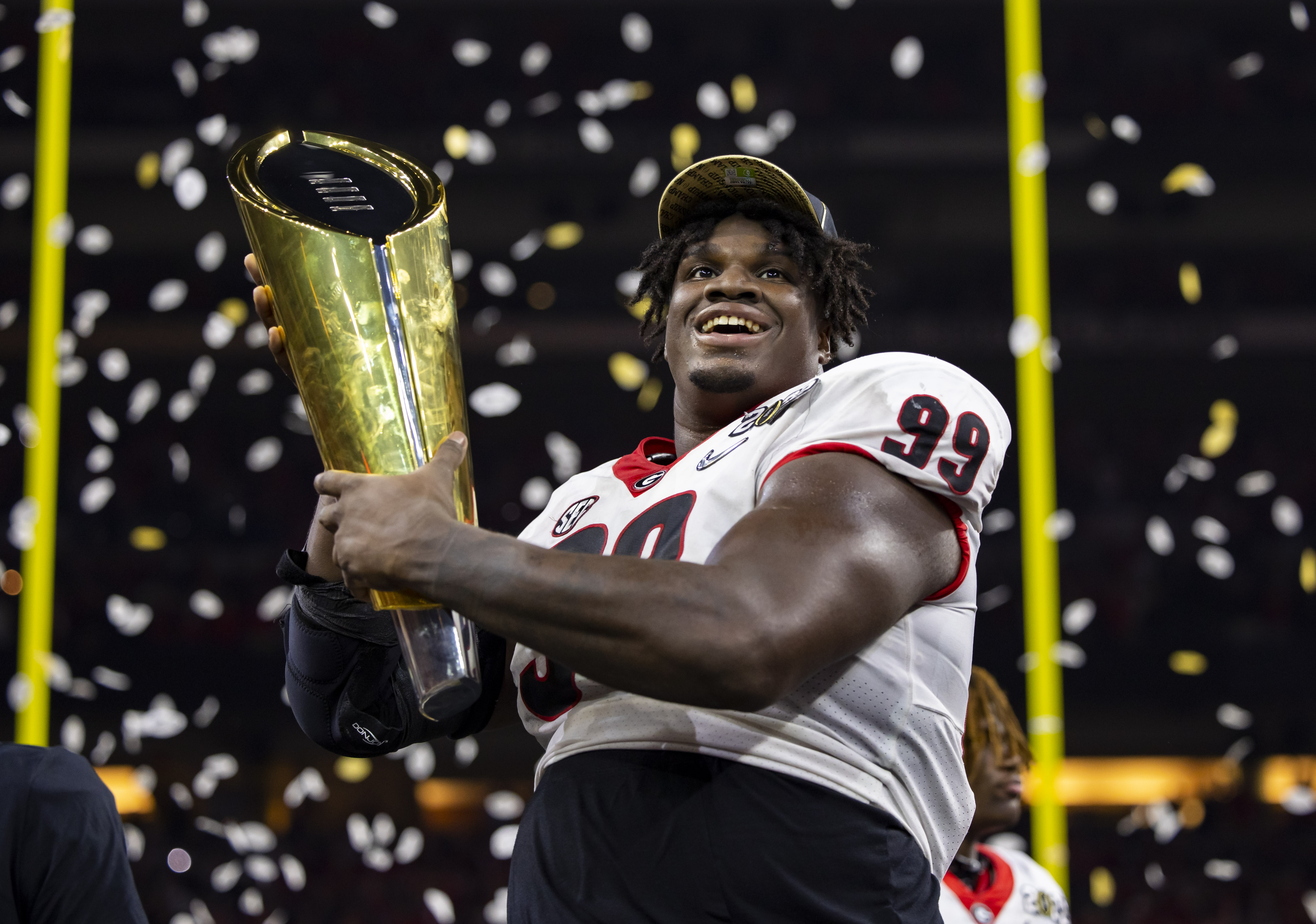 Georgia Bulldogs defensive lineman Jordan Davis (99) celebrates with the championship trophy after defeating the Alabama Crimson Tide in the 2022 CFP college football national championship game at Lucas Oil Stadium.
