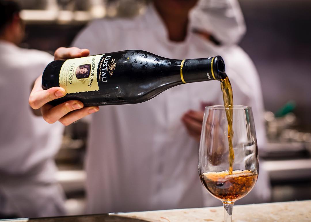 Pouring a bottle of Oloroso sherry into a glass on a marble bar at Barrafina Drury Lane
