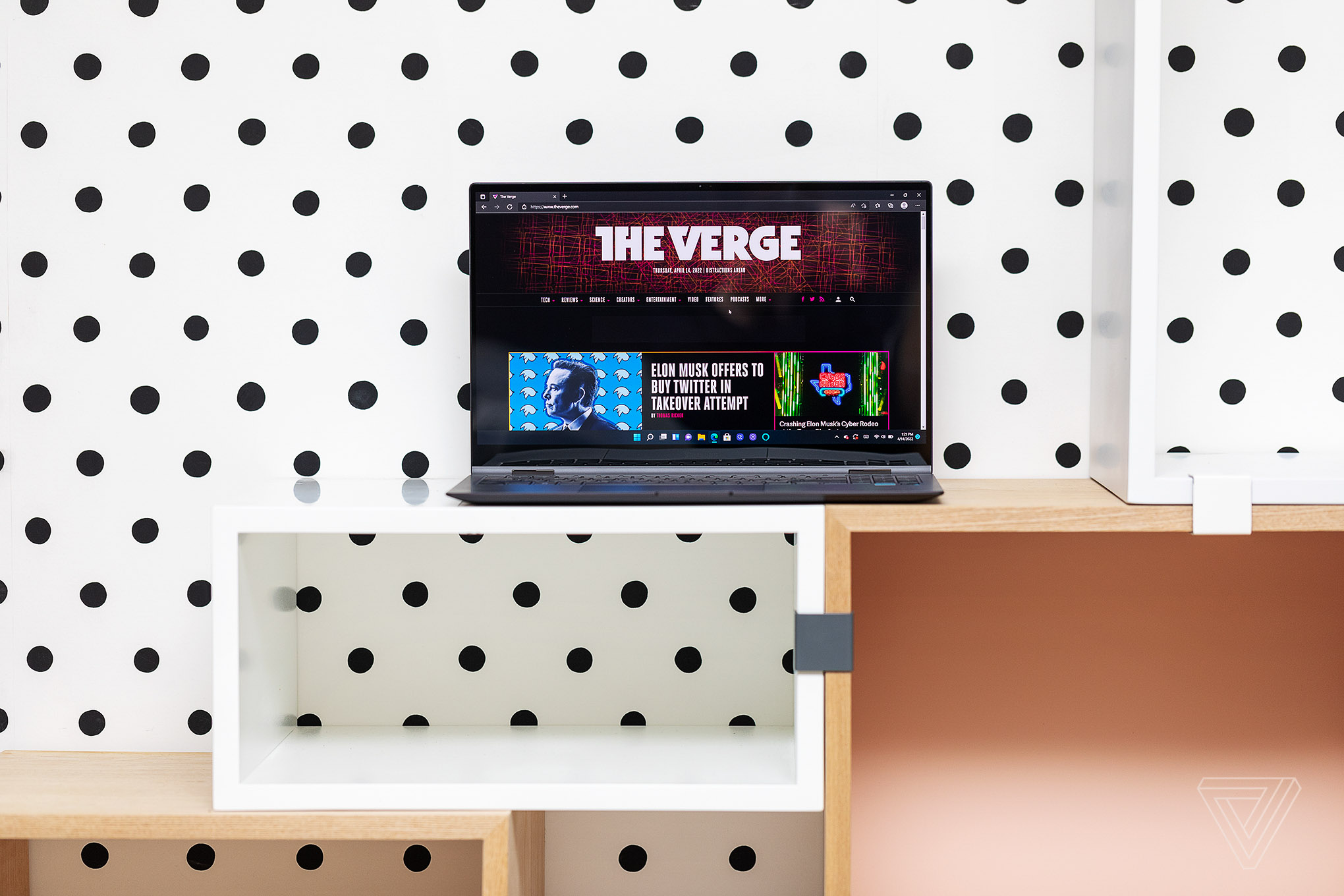 The Samsung Galaxy Book2 Pro 360 in front of polka dot wallpaper. The screen displays The Verge homepage.