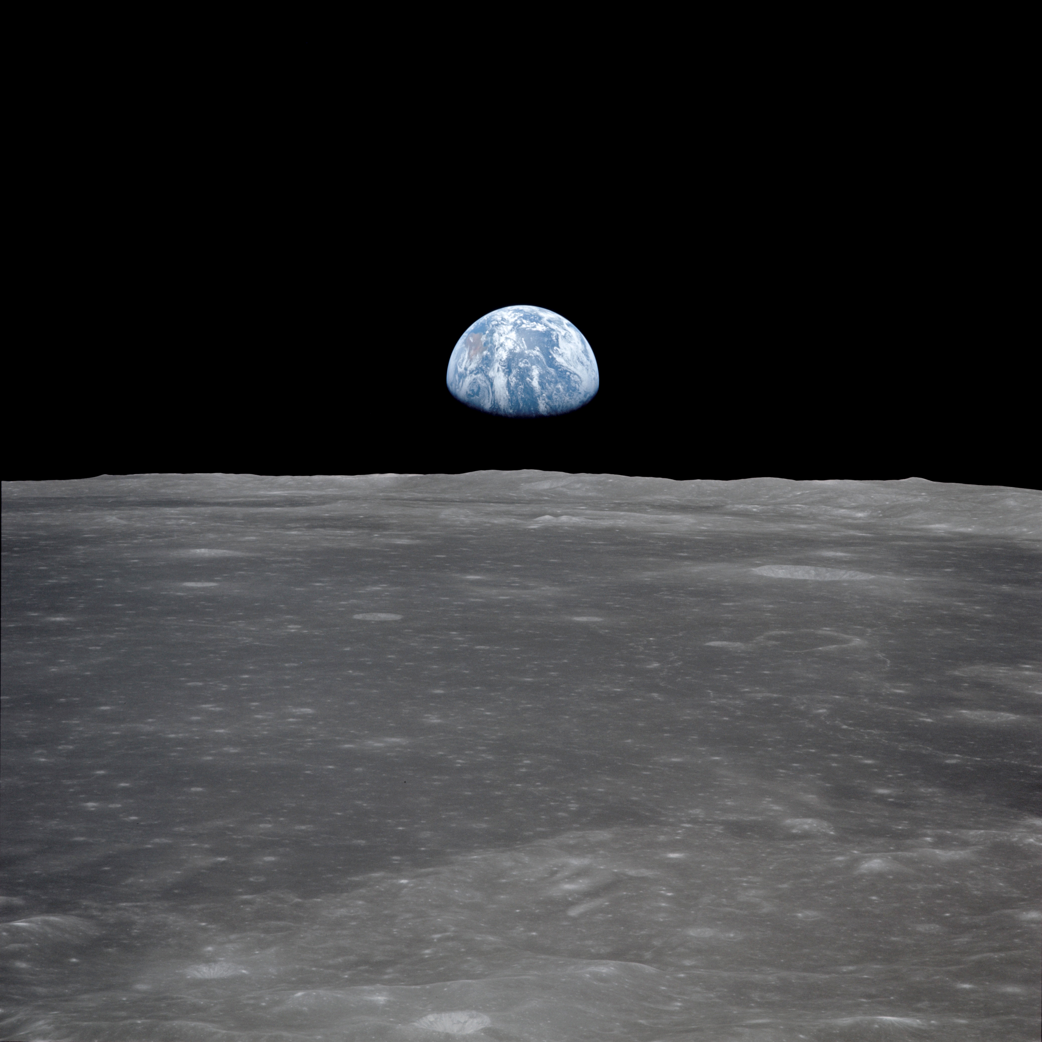 (July 1969) --- This view from the Apollo 11 spacecraft shows the Earth rising above the moon’s horizon. The lunar terrain pictured is in the area of Smyth’s Sea on the nearside