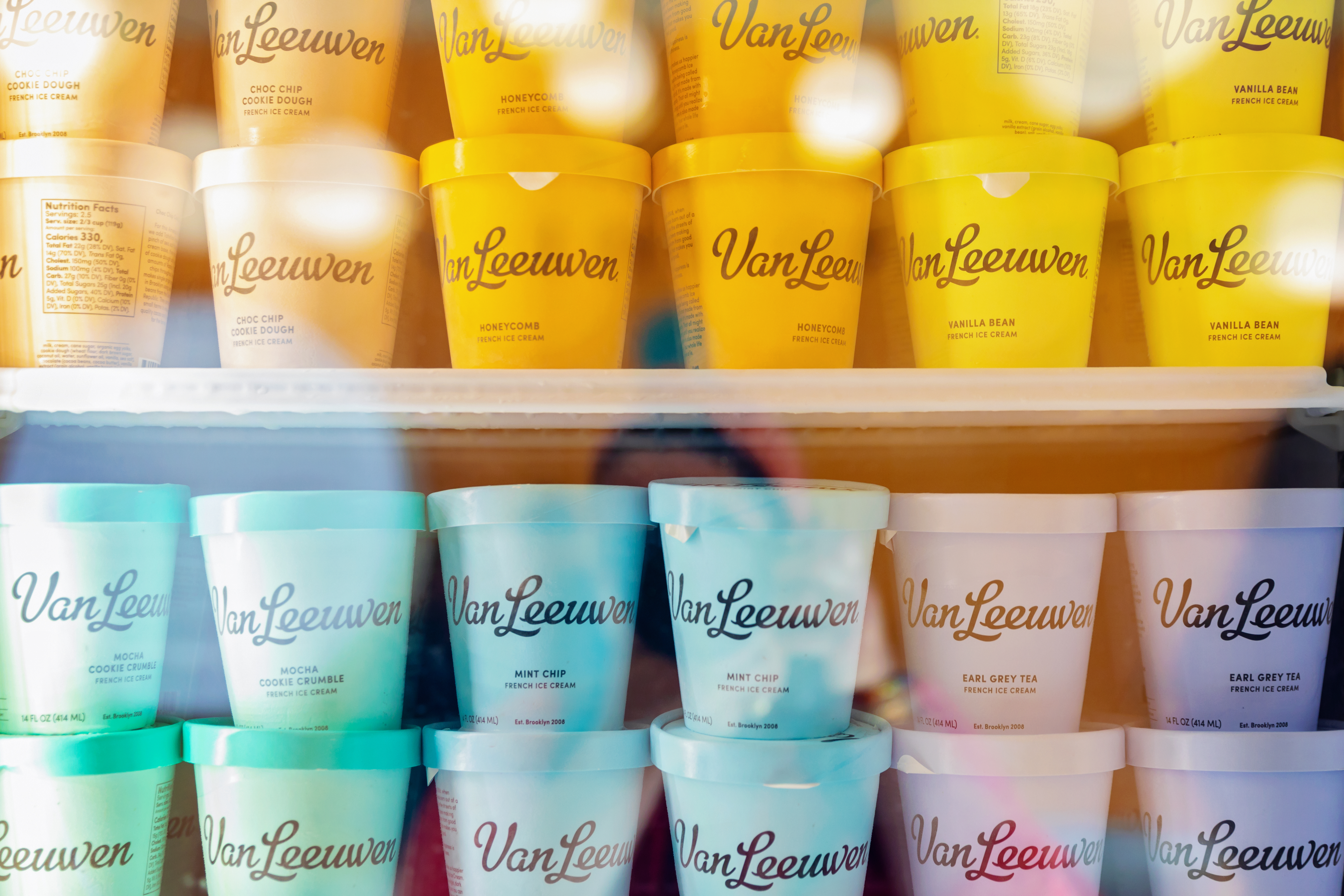 In freezer cases, dozens of containers of Van Leeuwen ice cream sit. They are orange, green, blue, and purple.