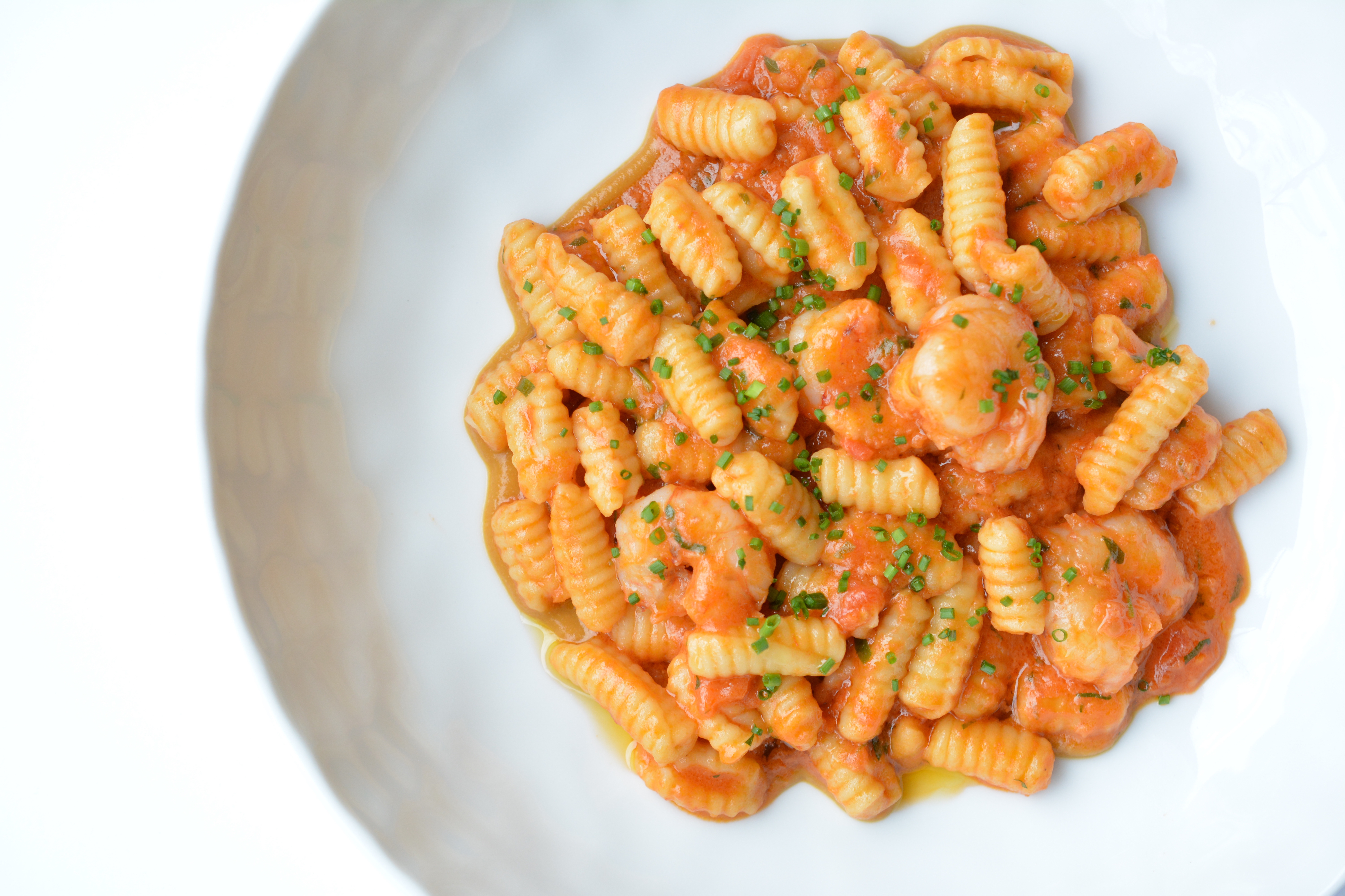 Ridged, oblong gnocchetti sit in a white bowl with a pink-ish tomato sauce