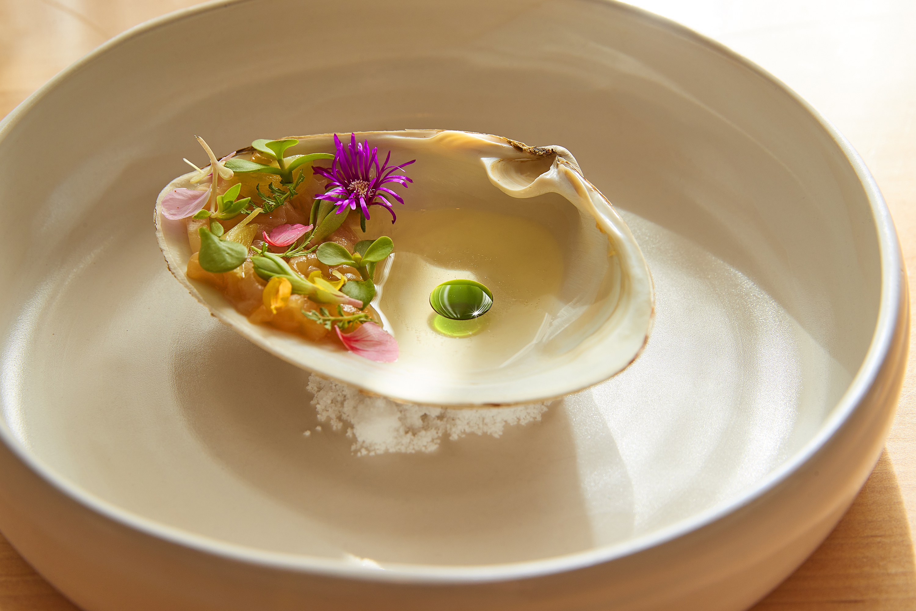 An oyster on a white plate.