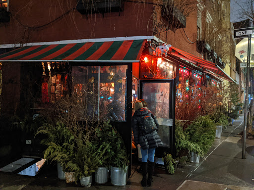 A nighttime photo of the exterior of the Spotted Pig, which has a red-and-green awning.