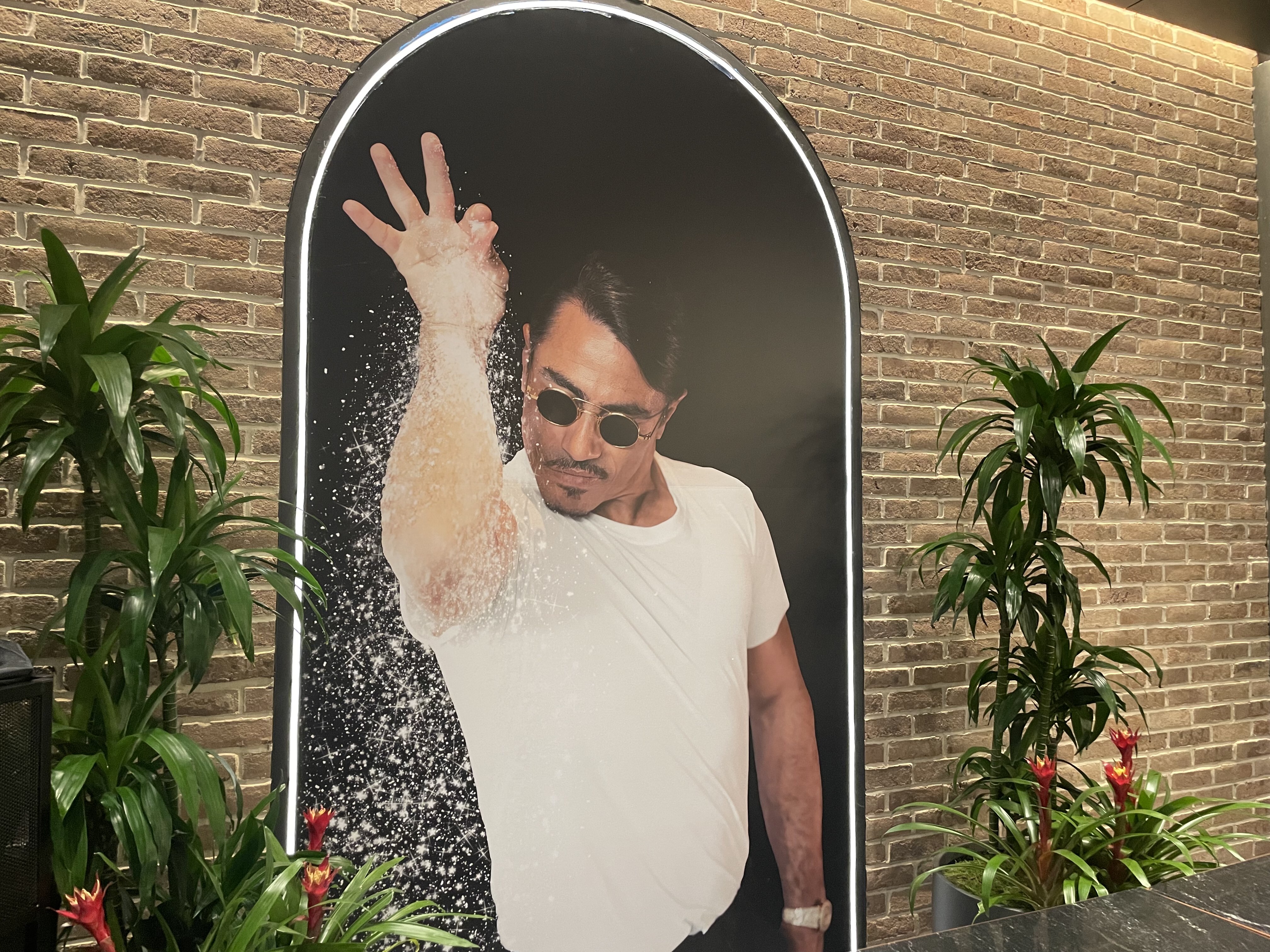 A paintig of Salt Bae hung on a brick wall inside Nusr-et’s latest steakhouse opening in NYC.