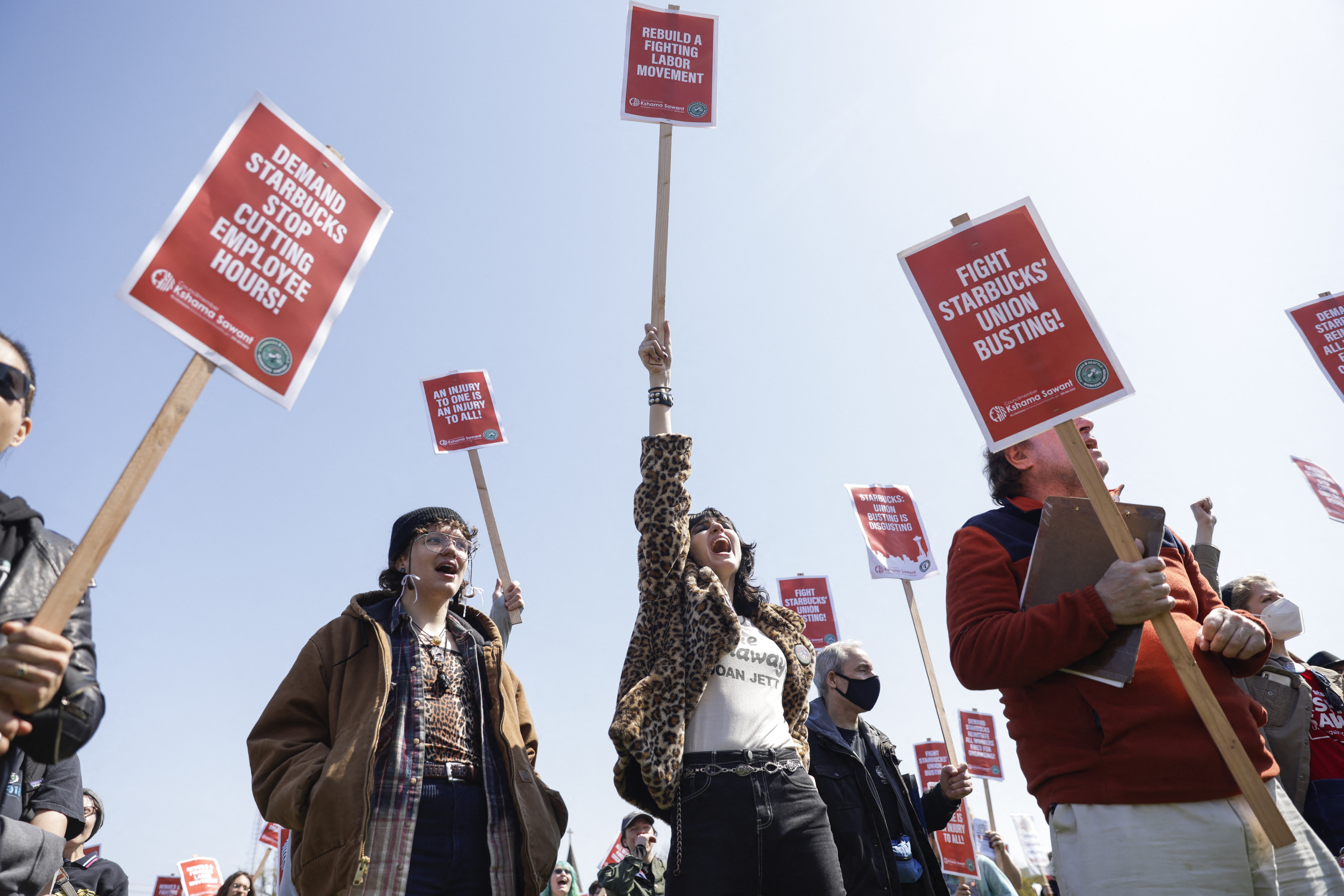 A crowd of people march while carrying picket signs in support of unionizing.