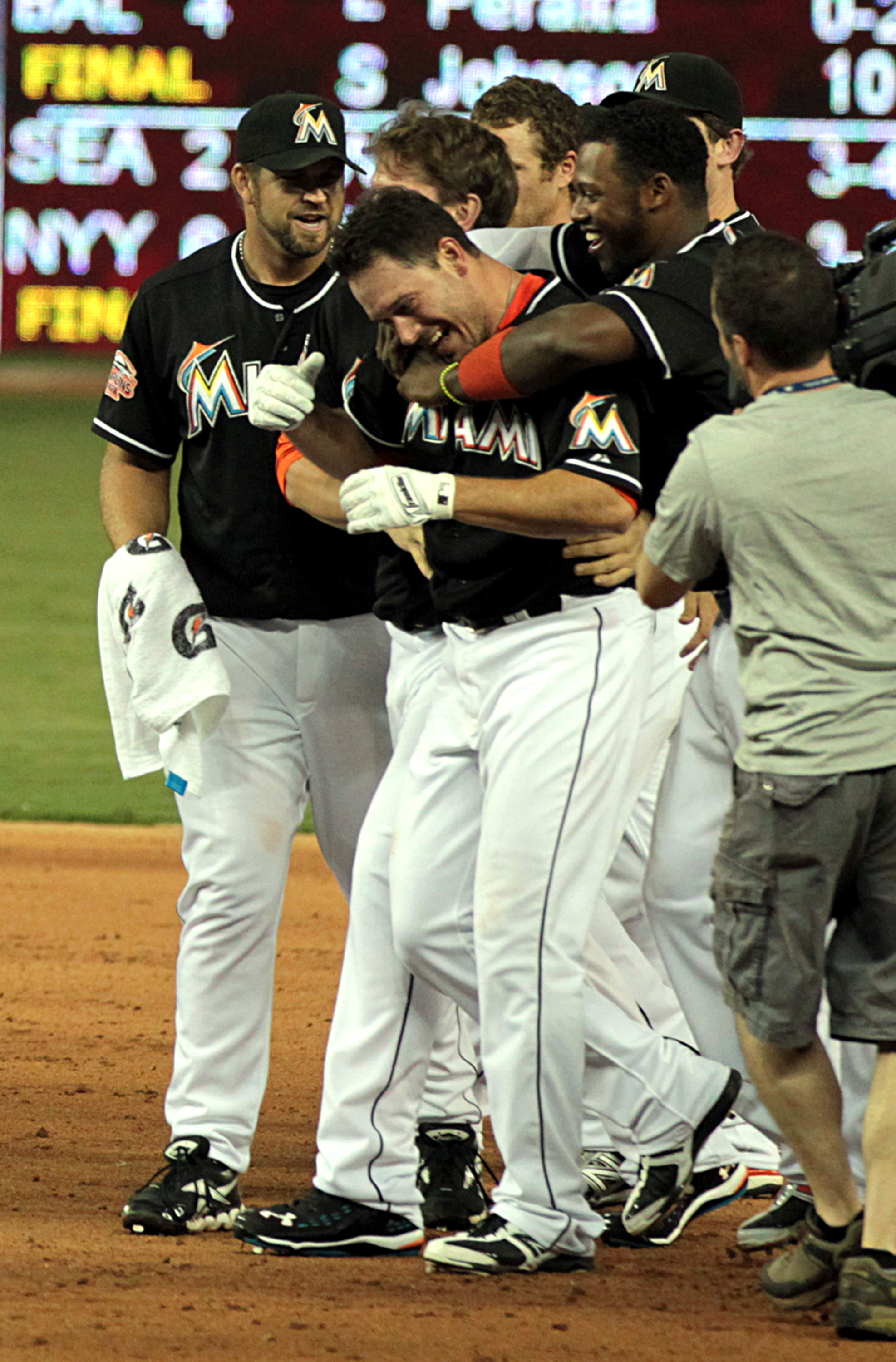 The Miami Marlins’ Hanley Ramirez, hugs teammate Greg Dobbs as they celebrate a 6-5 win against the New York Mets at Marlins Park in Miami, Florida