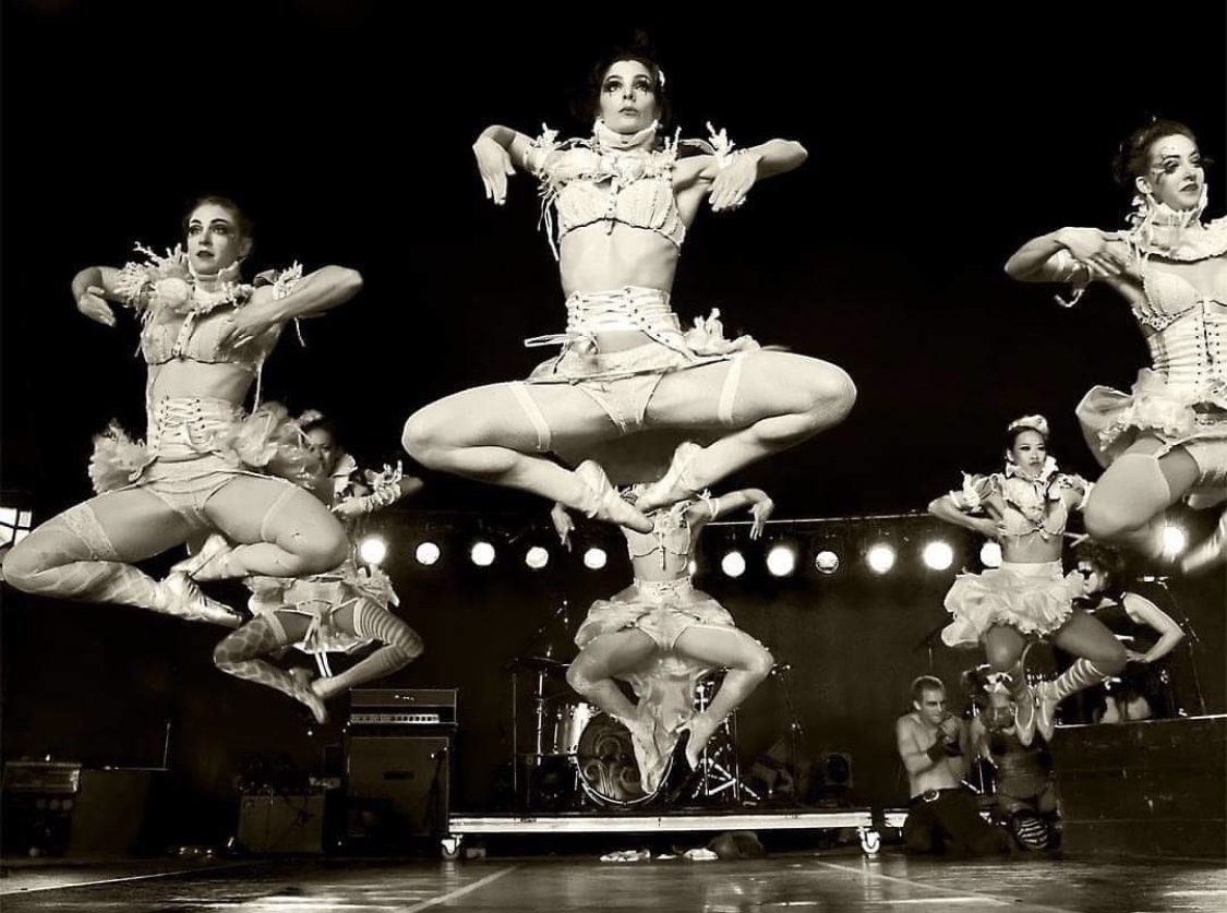 A black and white photo of dancing performers mid-flight.