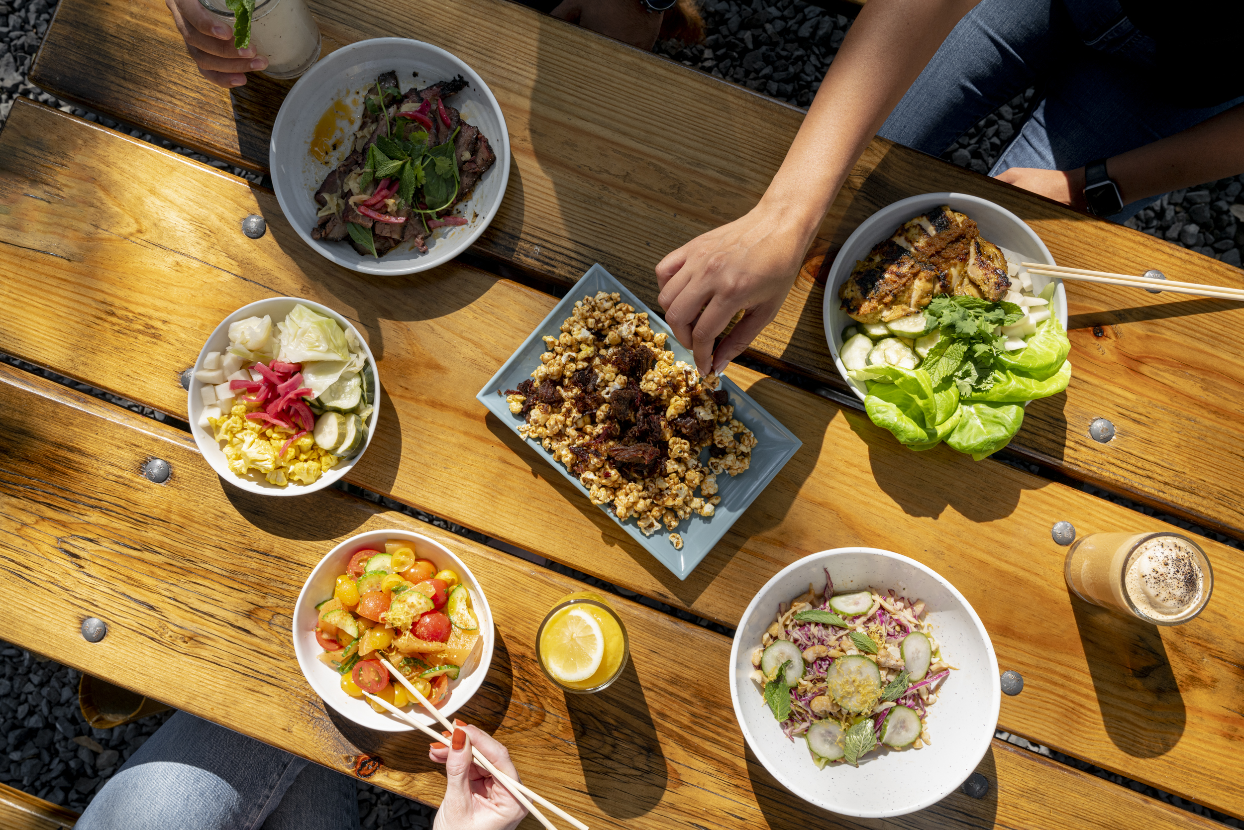 A table spread with Loro Houston’s candied kettle corn with burnt brisket ends, a rice bowl, a cold noodle salad, and slices of beef brisket with chile gastrique and Thai herbs.