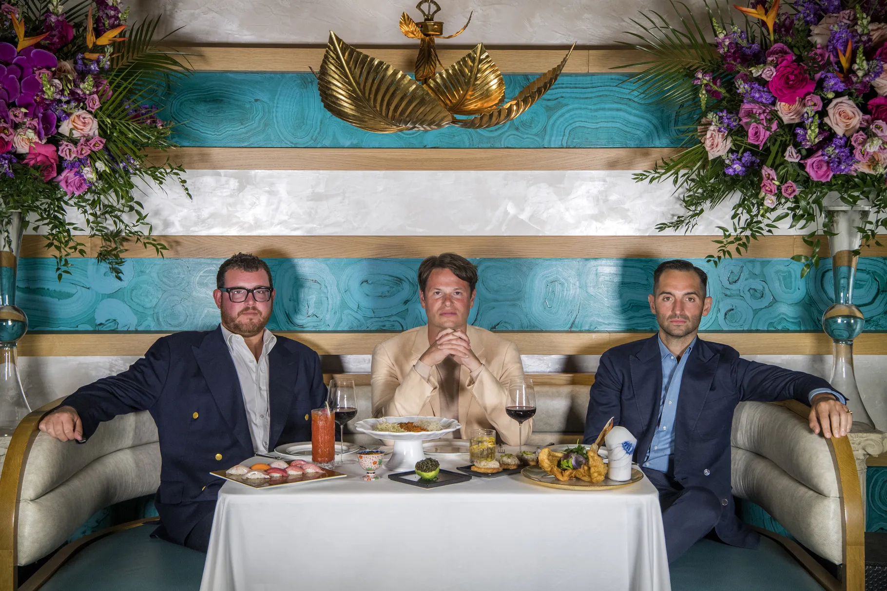 Jeff Zalaznick, Rich Torrisi, Mario Carbone of Major Food Group pose for a photograph in a colorful banquette.