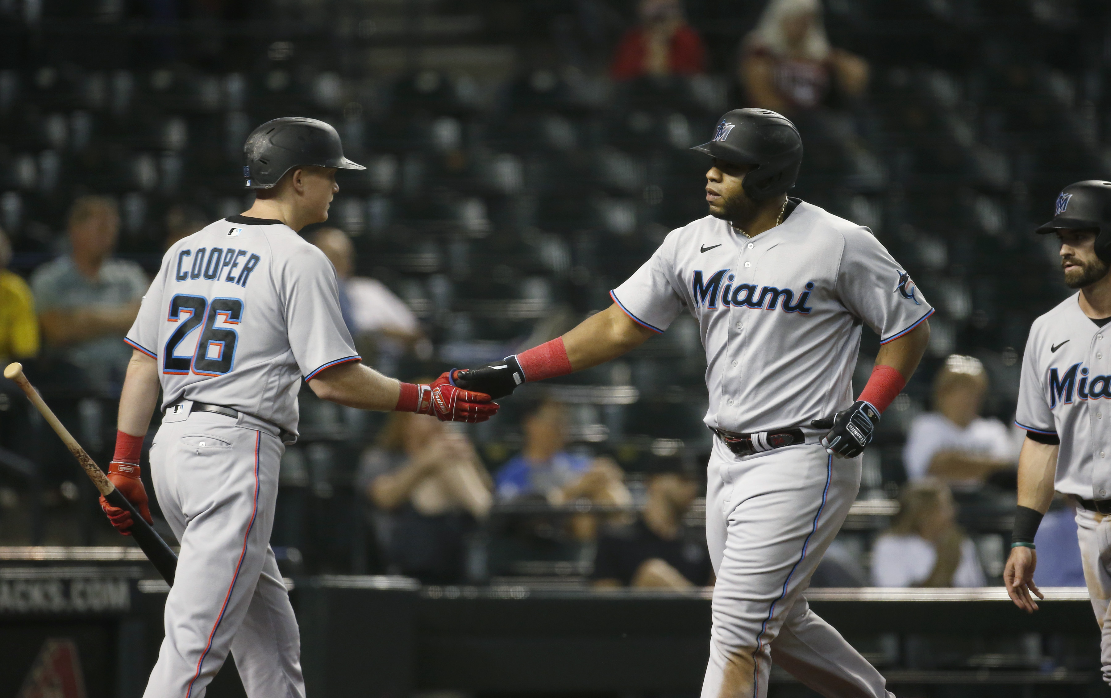 Jesus Aguilar #24 of the Miami Marlins is congratulated by Garrett Cooper #26 of the Marlins after hitting a two-run home run against the Arizona Diamondbacks during the eighth inning of the MLB game at Chase Field
