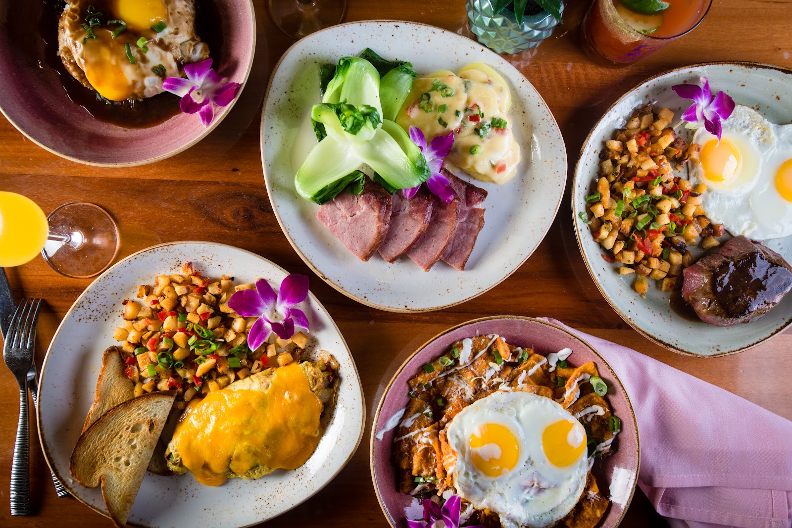 An overhead shot of a wooden table heavy with colorful brunch foods.