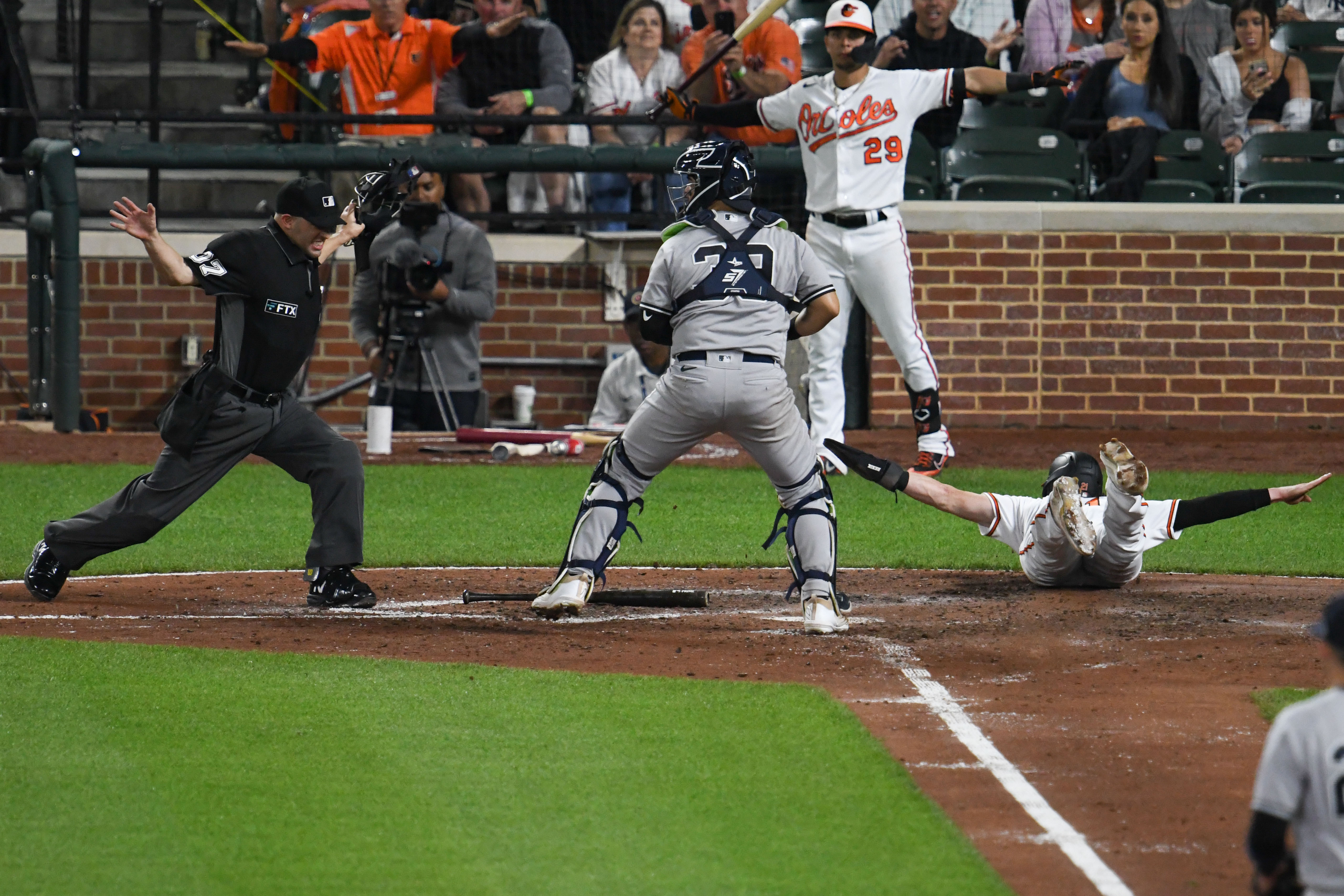 Austin Hays of the Orioles signals himself safe as he slides along the ground after scoring a run against the Yankees.