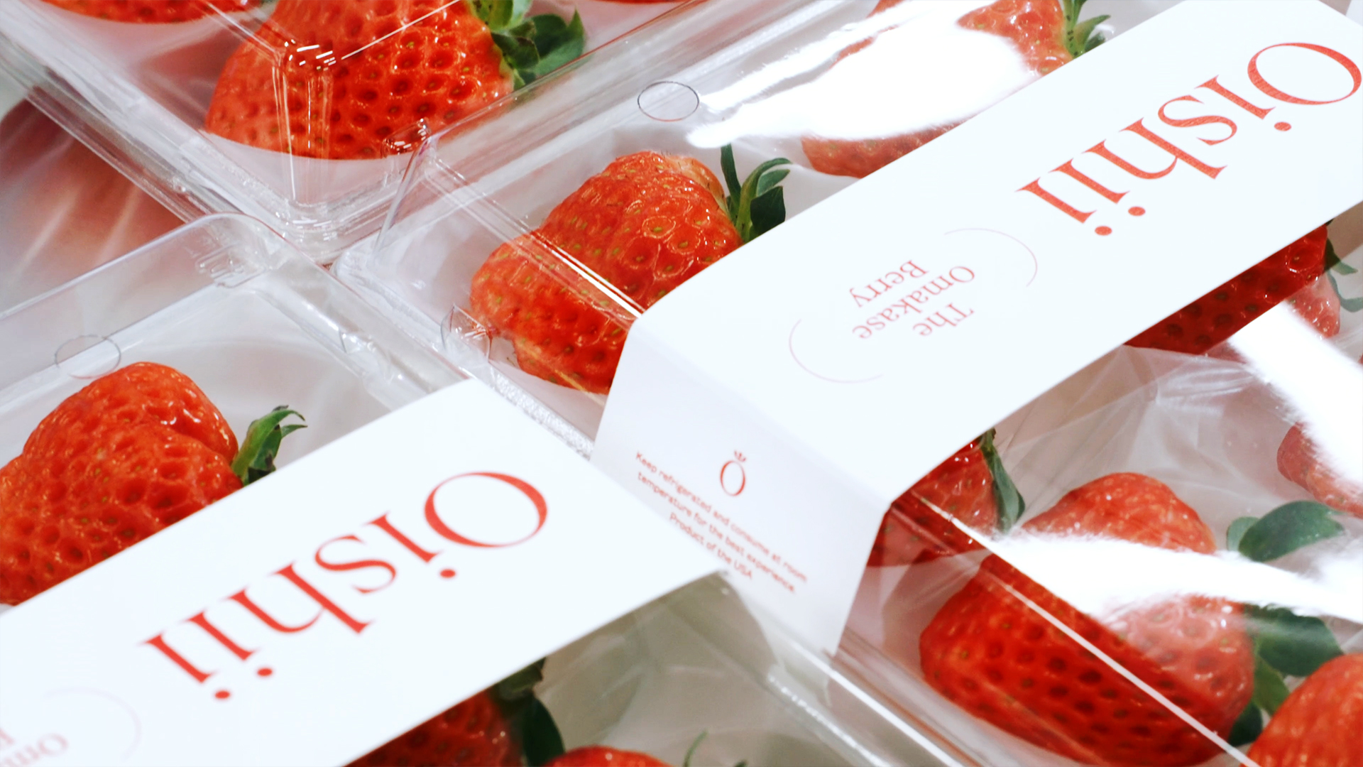 Strawberries, from upscale brand Oishii, are strewn out on a table in fancy branded packaging.