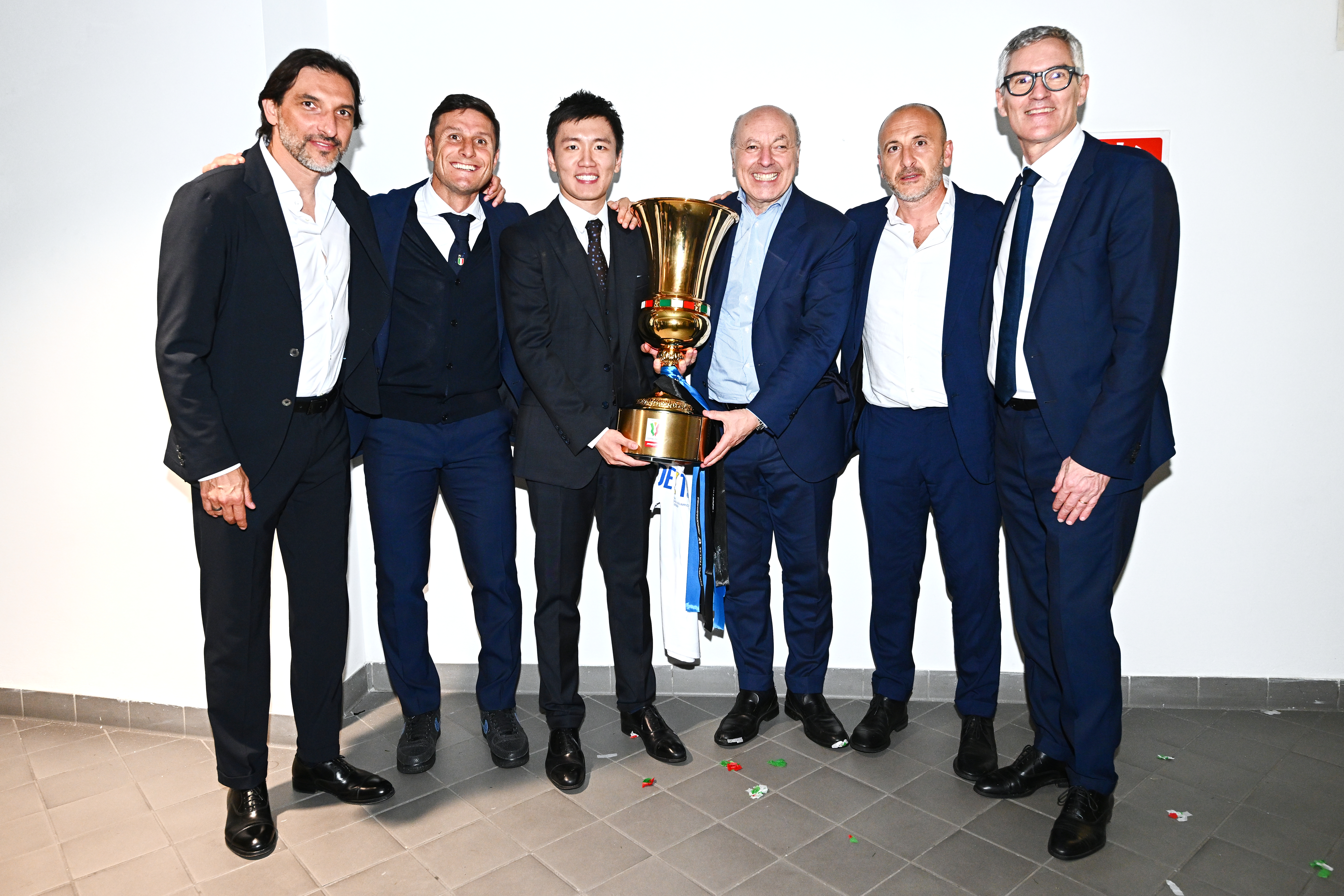 A Bunch of guys in suits hold a trophy in a boring white room