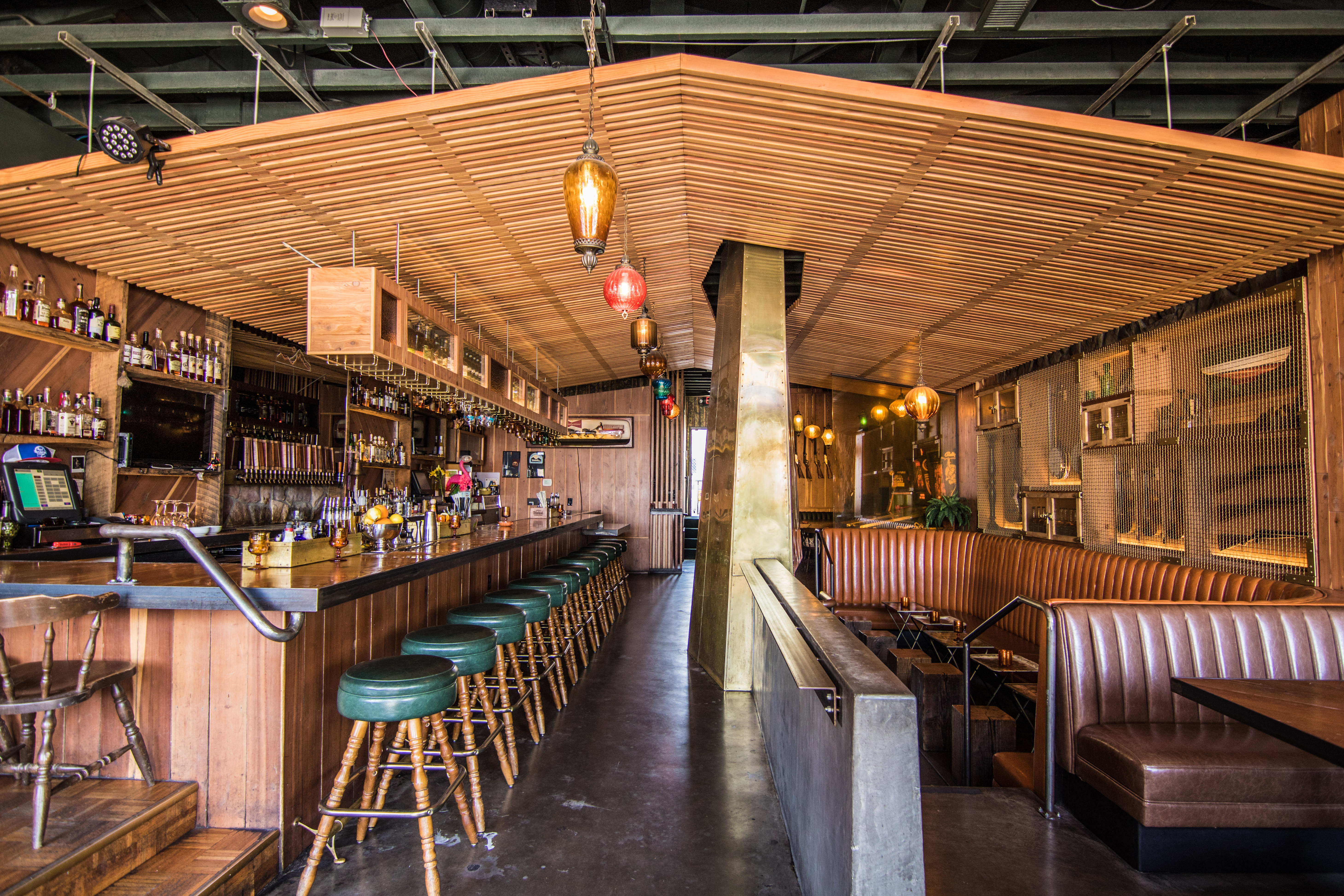 A wood-clad bar with bar stools and booths. 