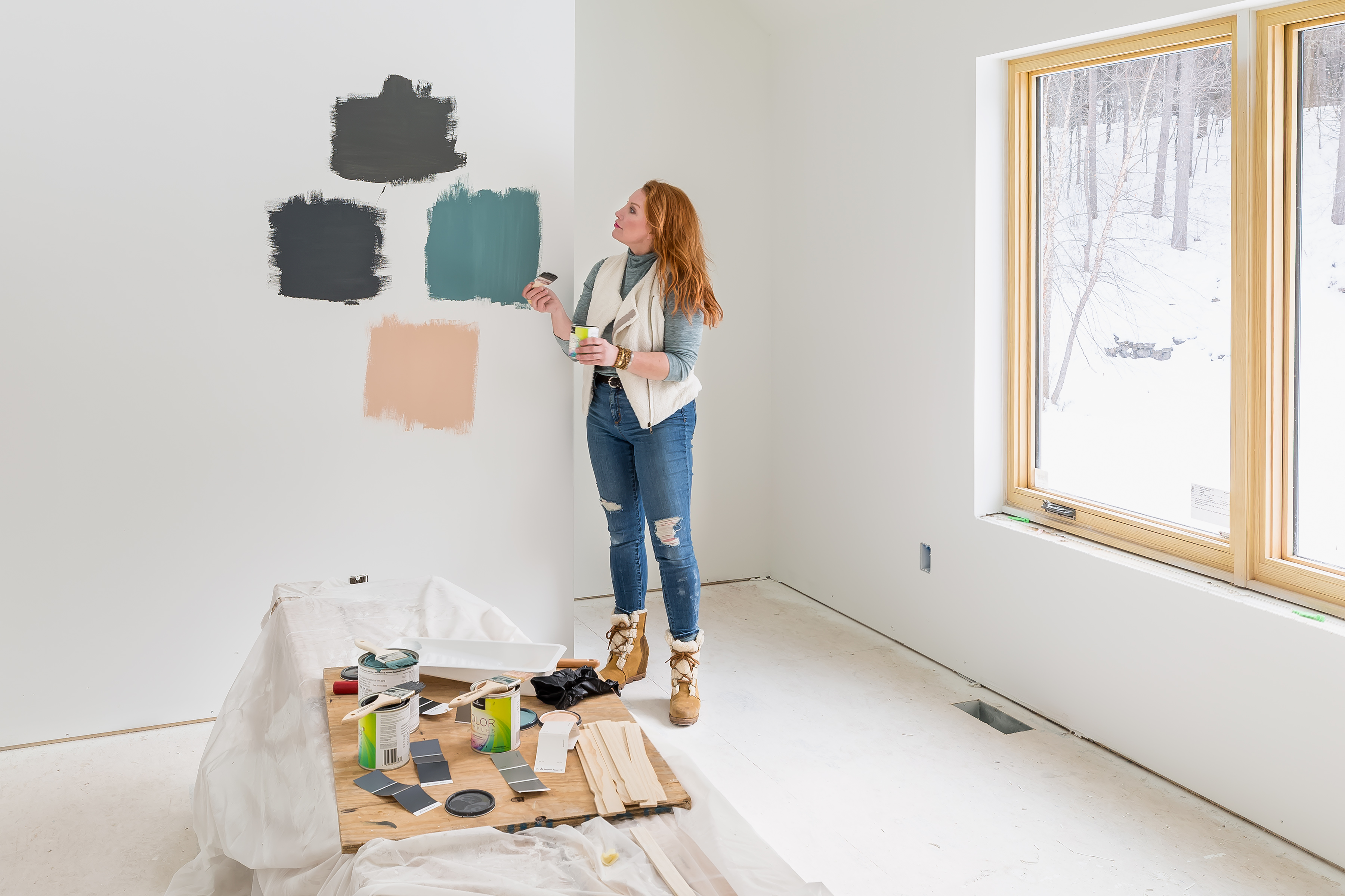 A woman putting up paint samples in a white room. 