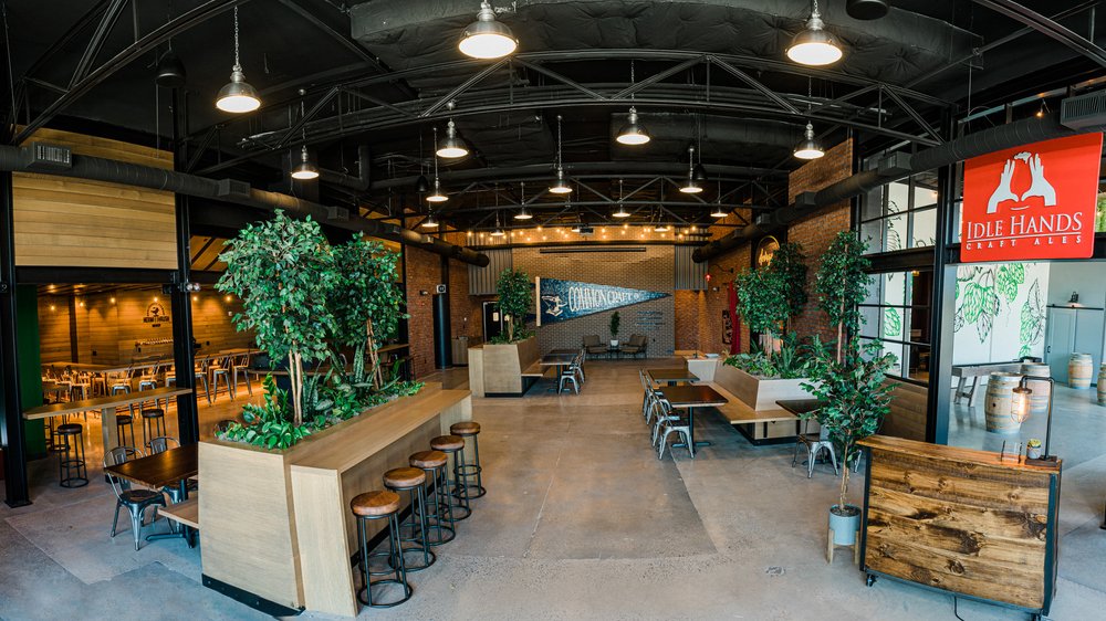 Interior view of an empty taproom with lots of wood accents and decorative trees.