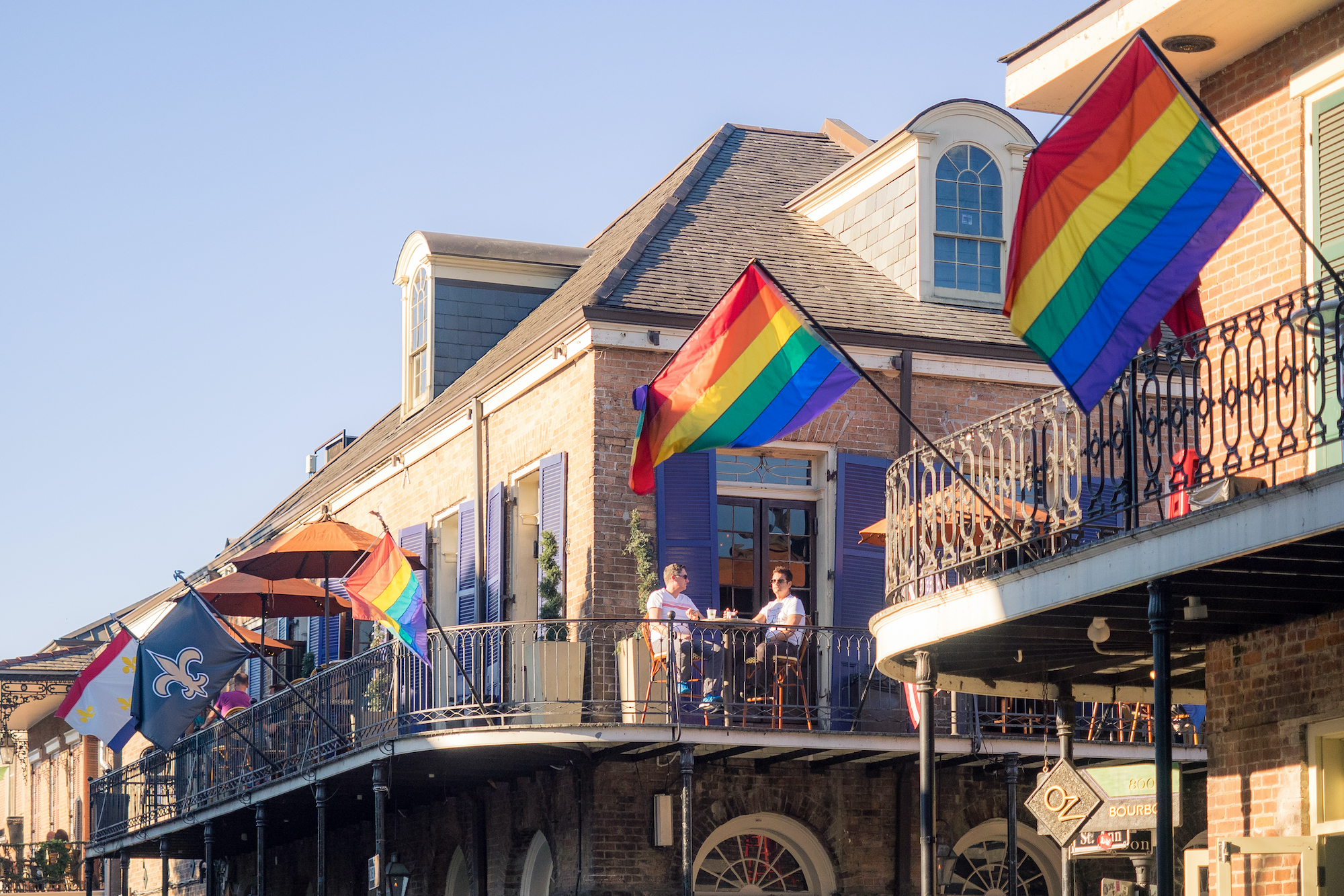 Two building terraces in the French Quarter wave pride flags.