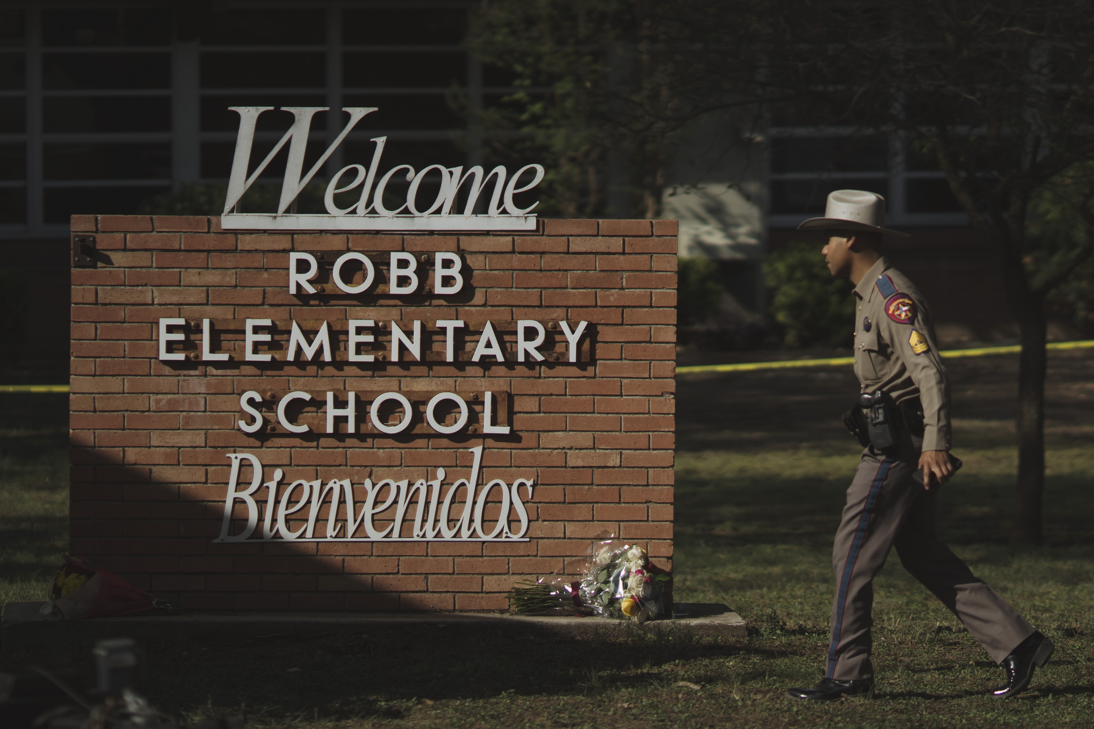 A law enforcement officer walks toward the “welcome” sign in front of Robb Elementary School in Uvalde, Texas.