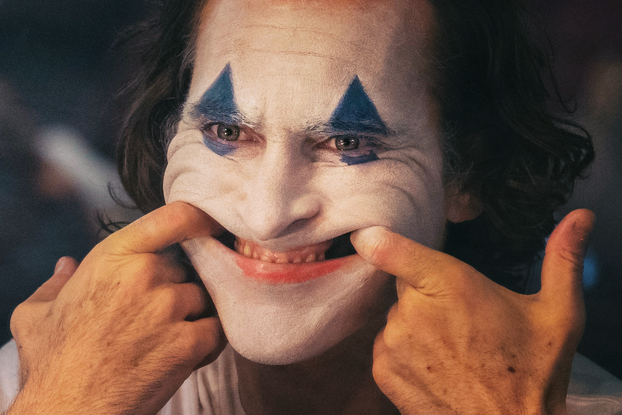 Joaquin Phoenix as the Joker pulls his mouth into a demonic grin