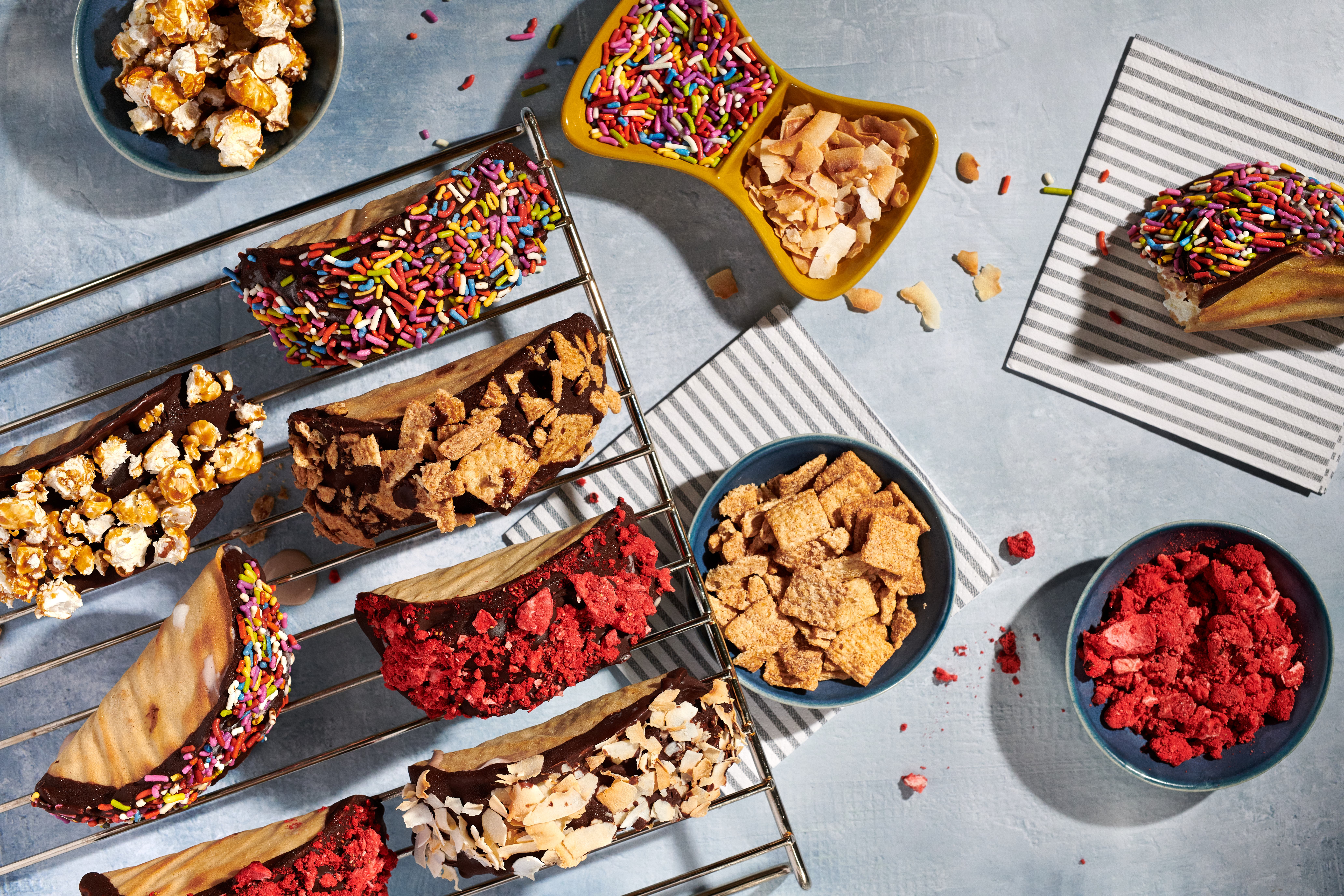 An array of ice cream tacos, covered in colorful toppings.