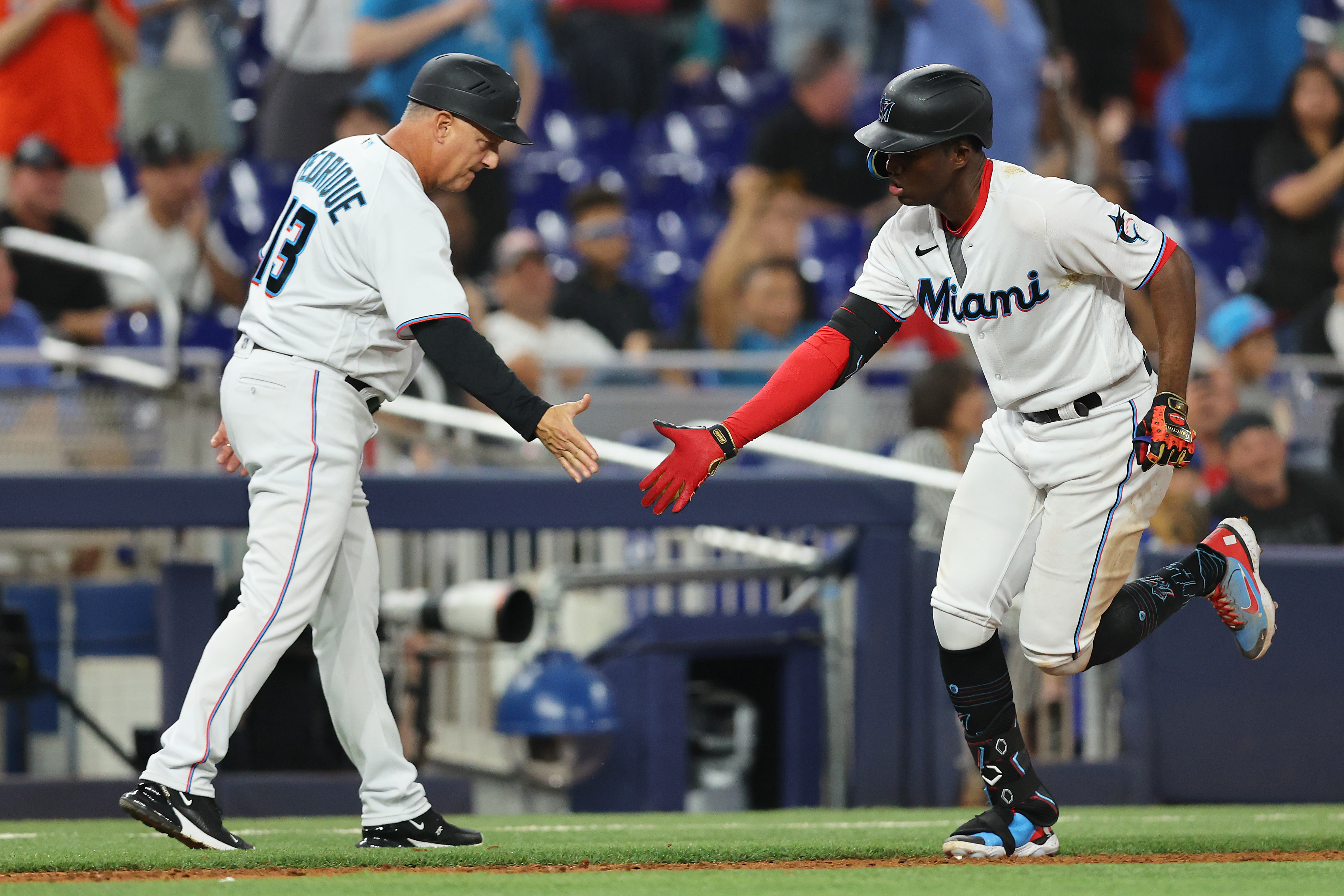 Jesus Sanchez #7 of the Miami Marlins high fives third base coach Al Pedrique #13 after hitting a two-run home run against the Washington Nationals during the fifth inning at loanDepot park on June 09, 2022 in Miami, Florida.