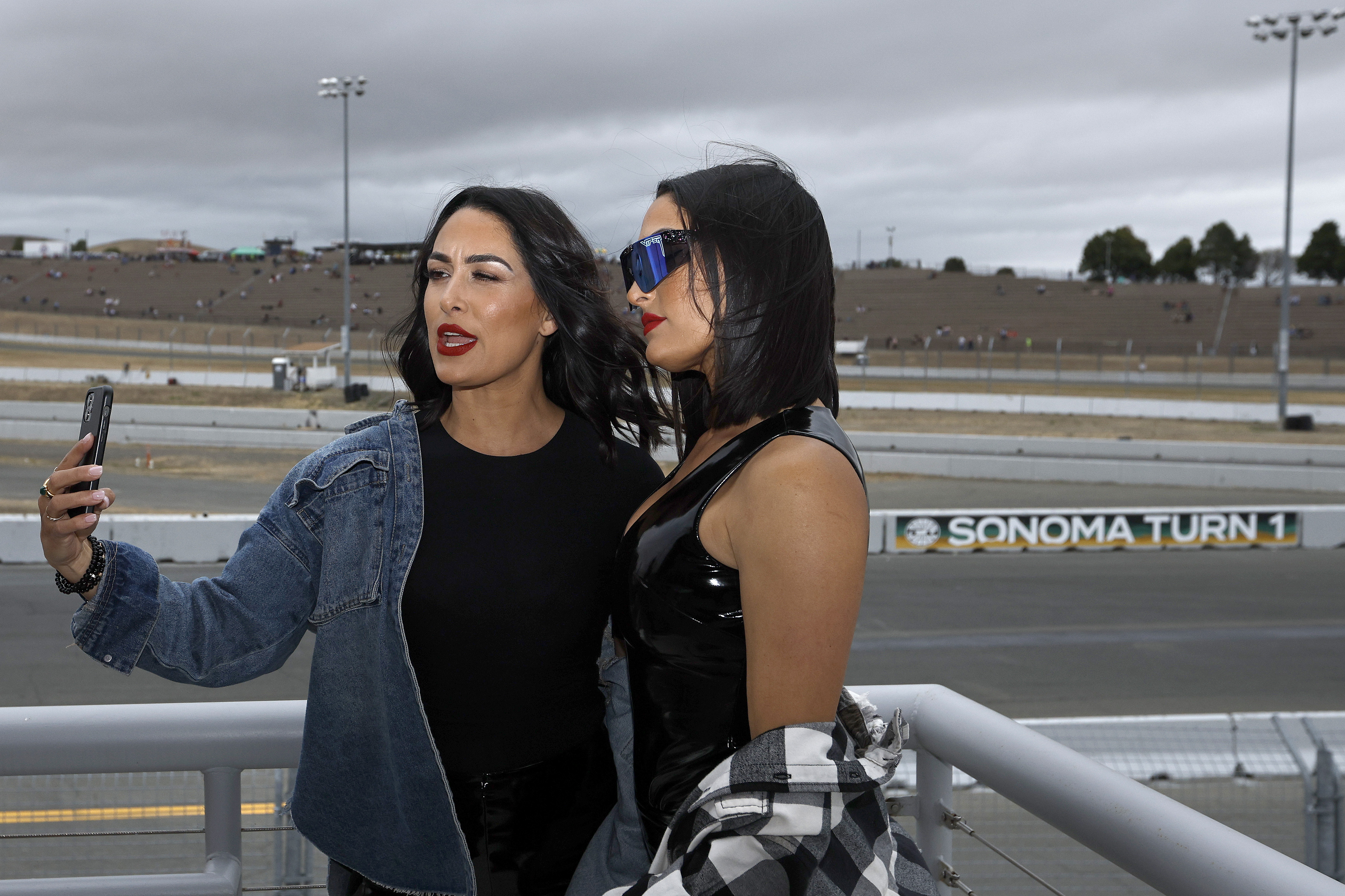 WWE wrestlers Brie Bella and Nikki Bella pose for photos on the midway prior to the NASCAR Cup Series Toyota/Save Mart 350 at Sonoma Raceway on June 12, 2022 in Sonoma, California.