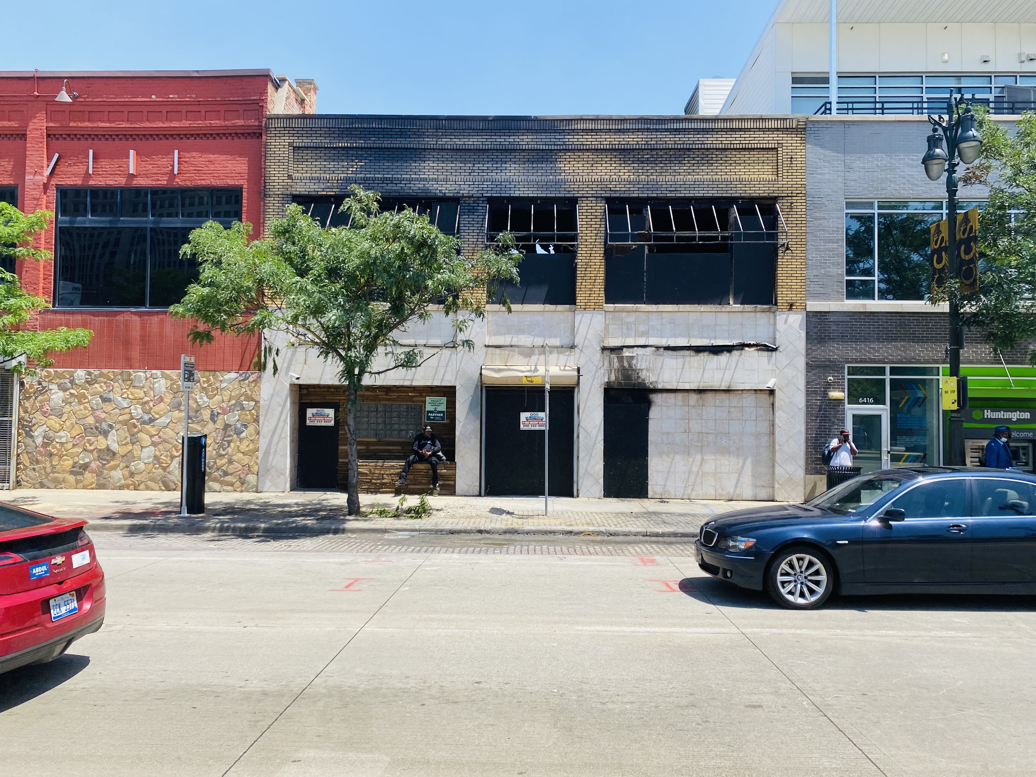 A brick building partially boarded up with fire and smoke damage visible on the exterior on Woodward Avenue in Detroit’s New Center area