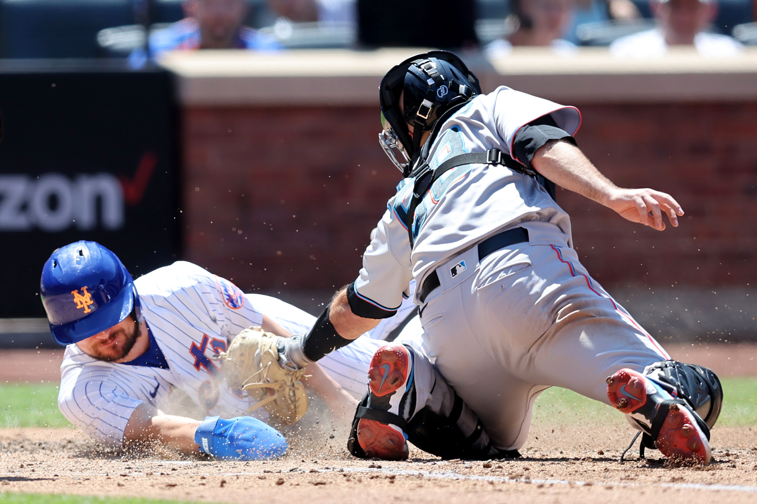 New York Mets designated hitter J.D. Davis (28) scores on a sacrifice fly by third baseman Eduardo Escobar (not pictured) ahead of the tag by Miami Marlins catcher Jacob Stallings (58) during the fourth inning at Citi Field.