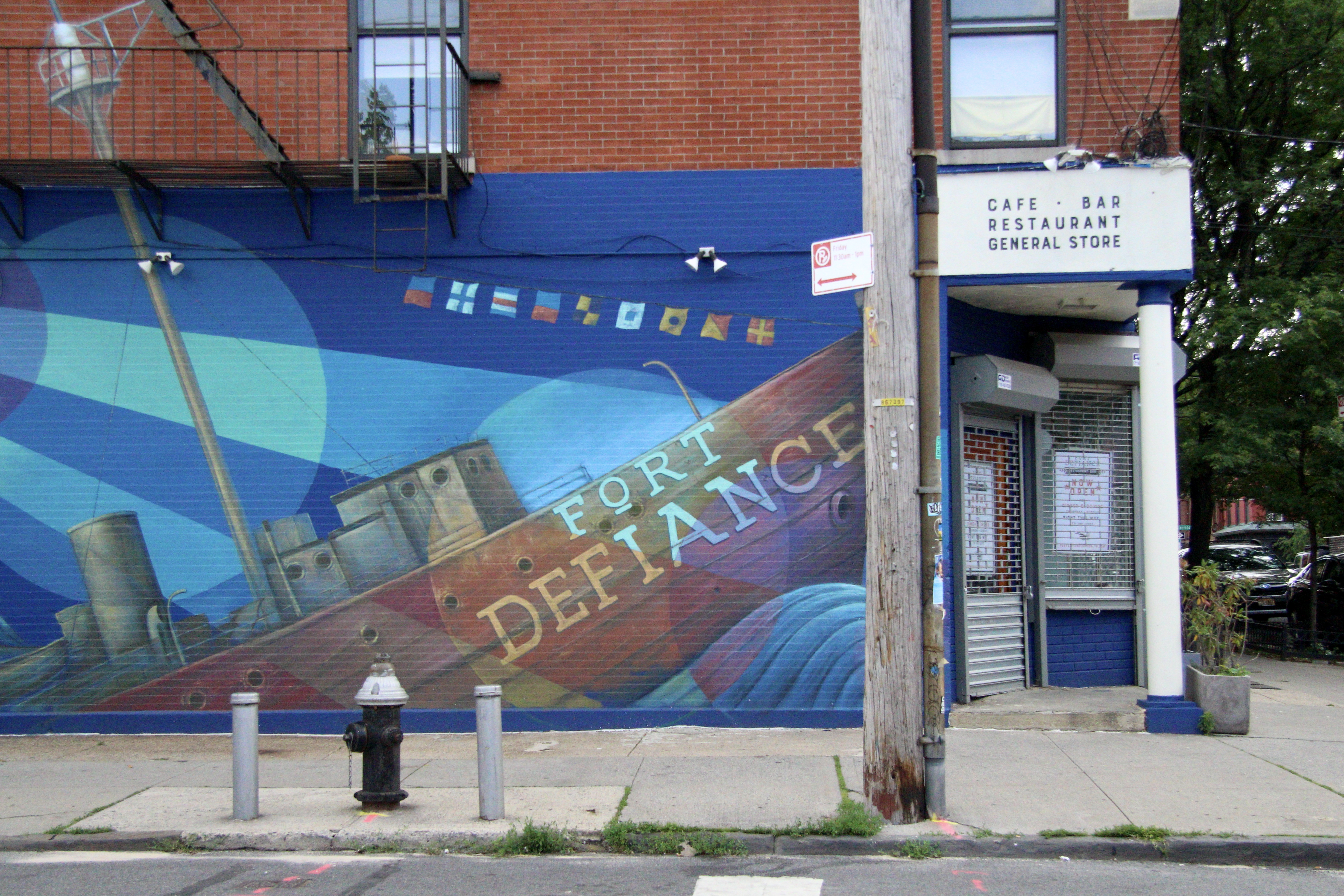 A blue brick restaurant exterior with a ship mural painted on the side.