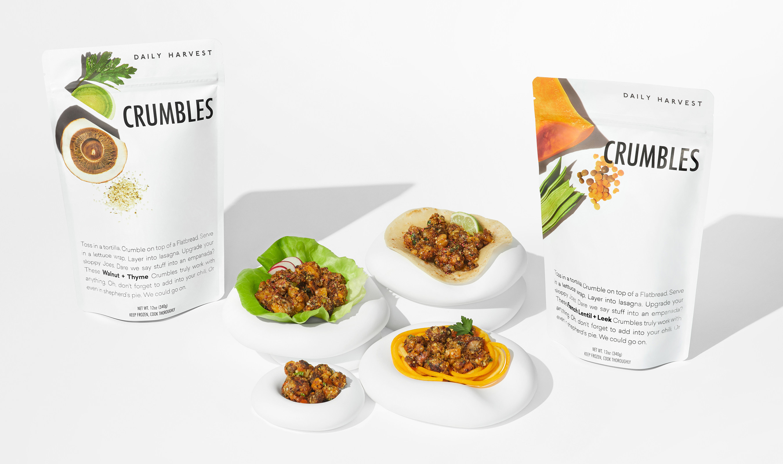 a promotional image showing two bags of Daily Harvest’s Crumbles, a plant-based protein product; between them are four dishes using the Crumbles