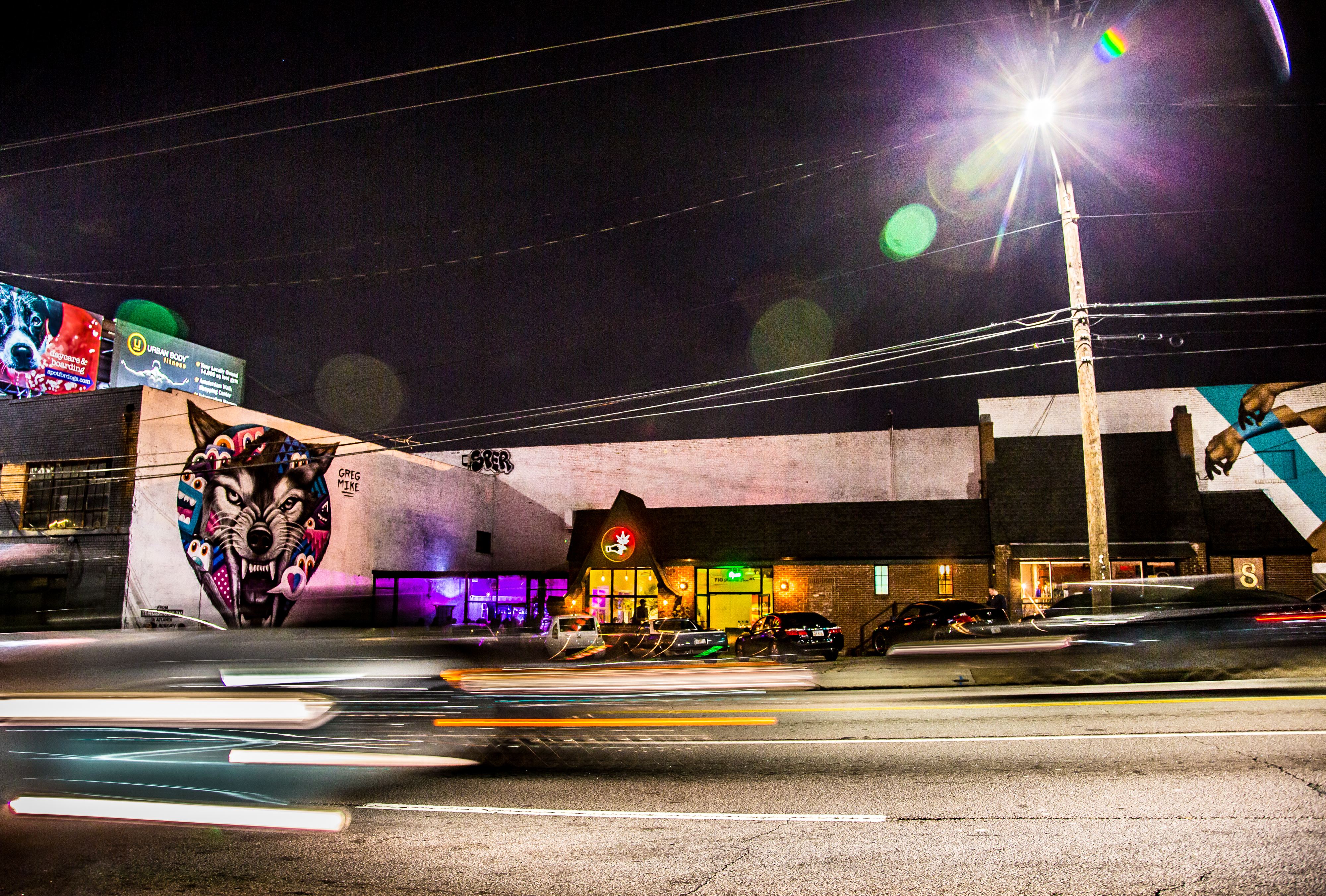A nighttime shot of restaurant and bar 8ARM located on Ponce de Leon Avenue in Atlanta with cars rushing by