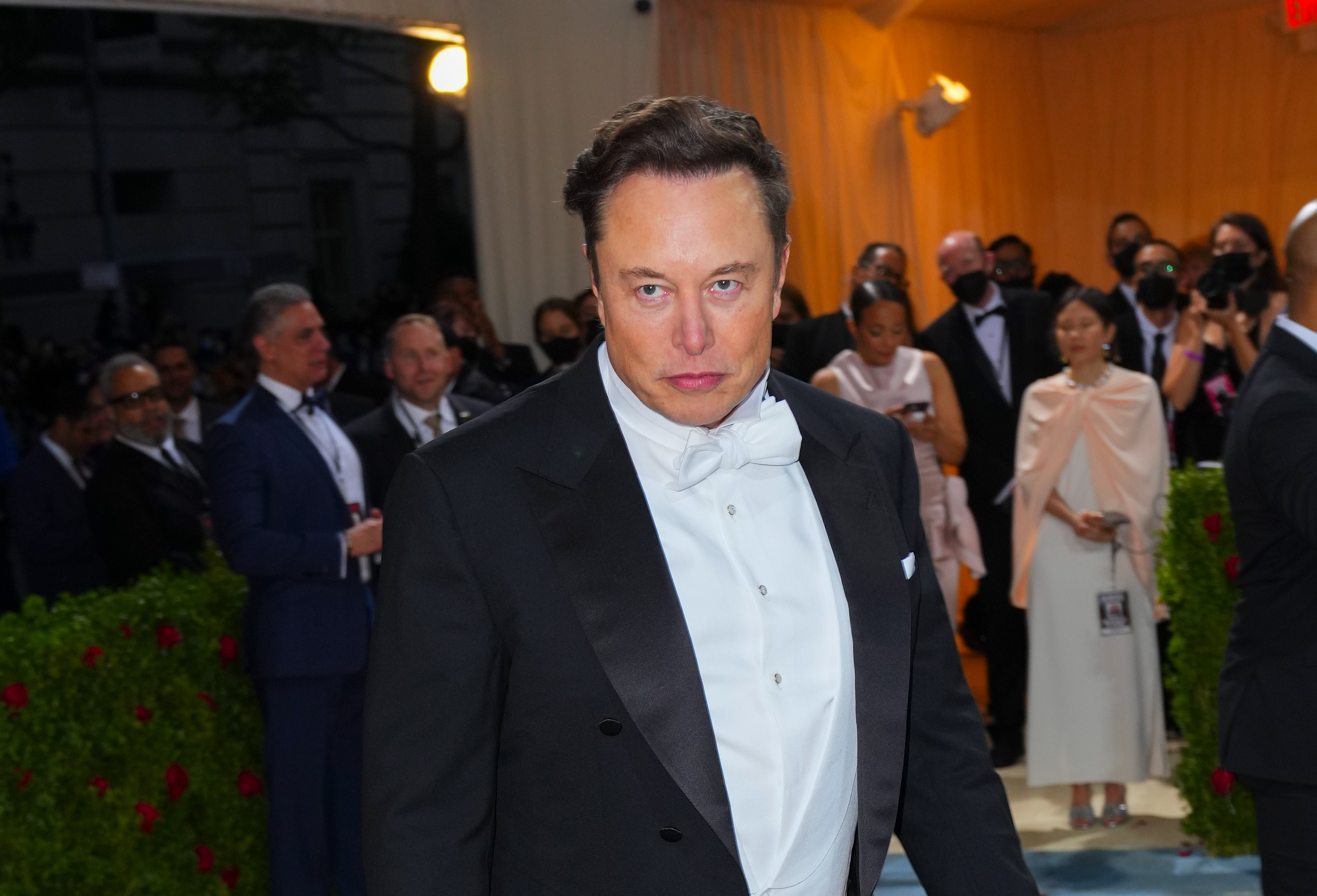 A photo of Elon Musk in a tuxedo from the waist up with a serious expression.