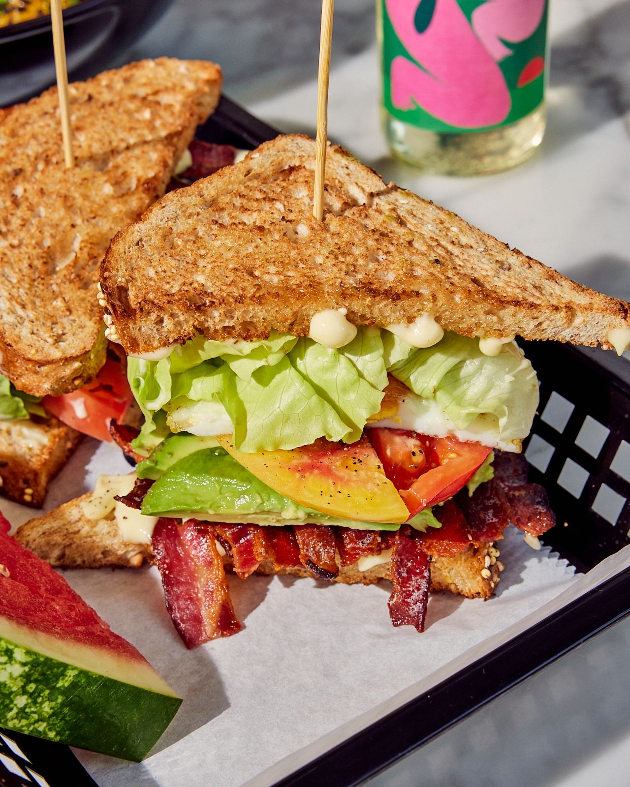 A sandwich with lettuce and bacon strips and other vegetables.