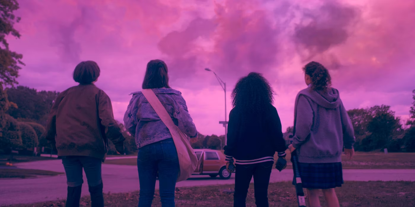 Paper Girls - Four newspaper delivery girls look up at ominous purple skies in a suburban neighborhood